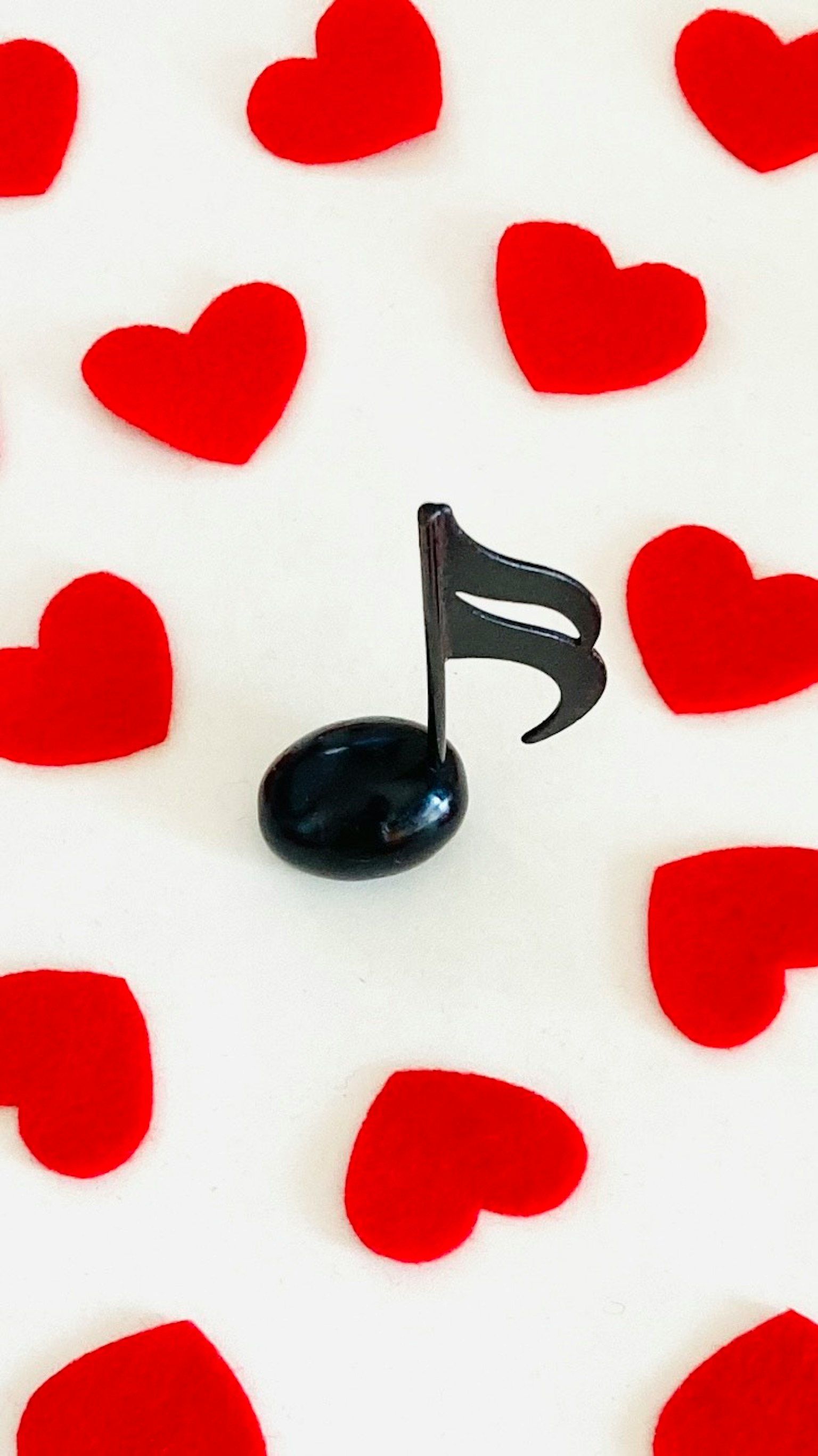 Nota musical negra rodeada de corazones rojos