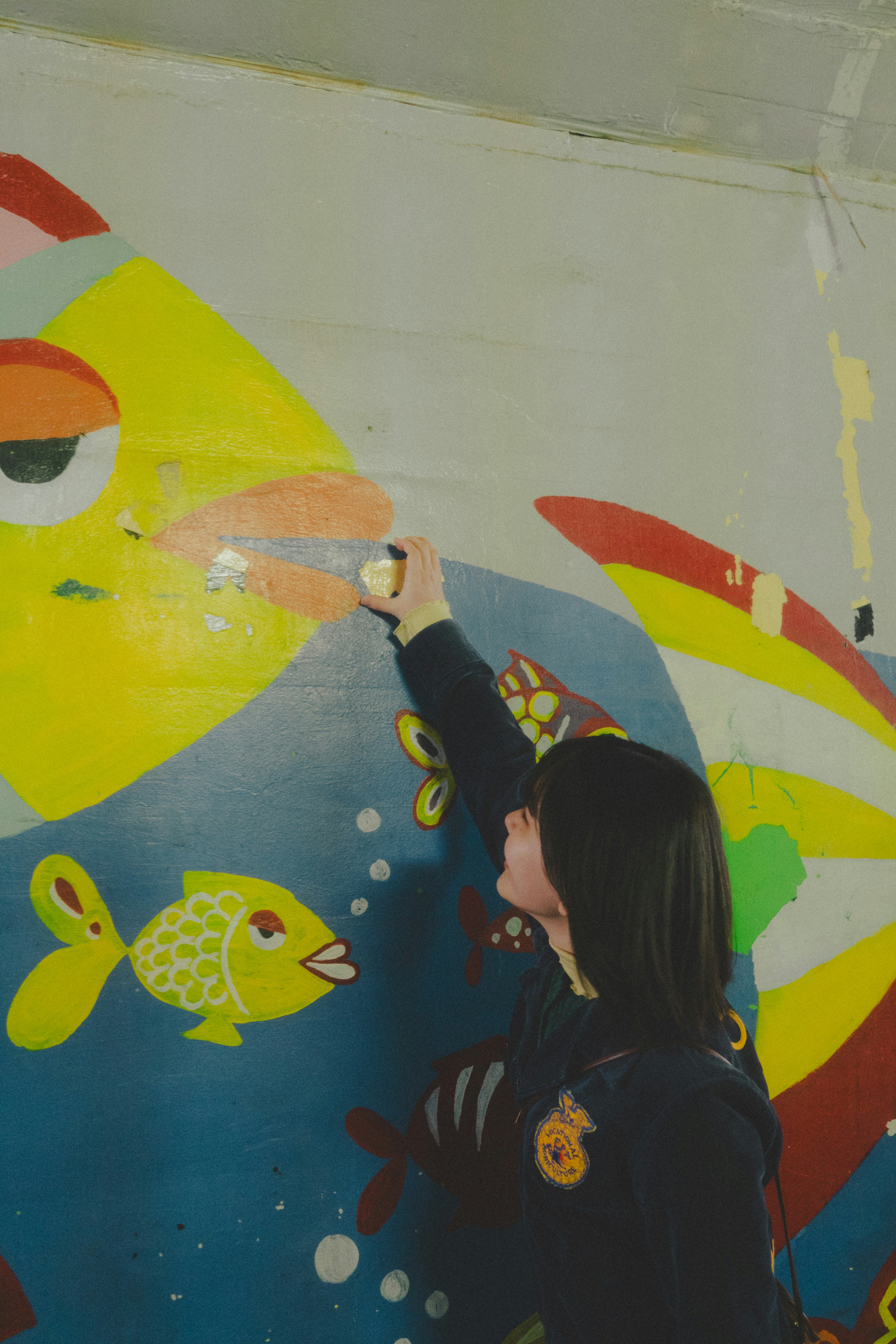 persona mirando un muro con graffitis de peces coloridos