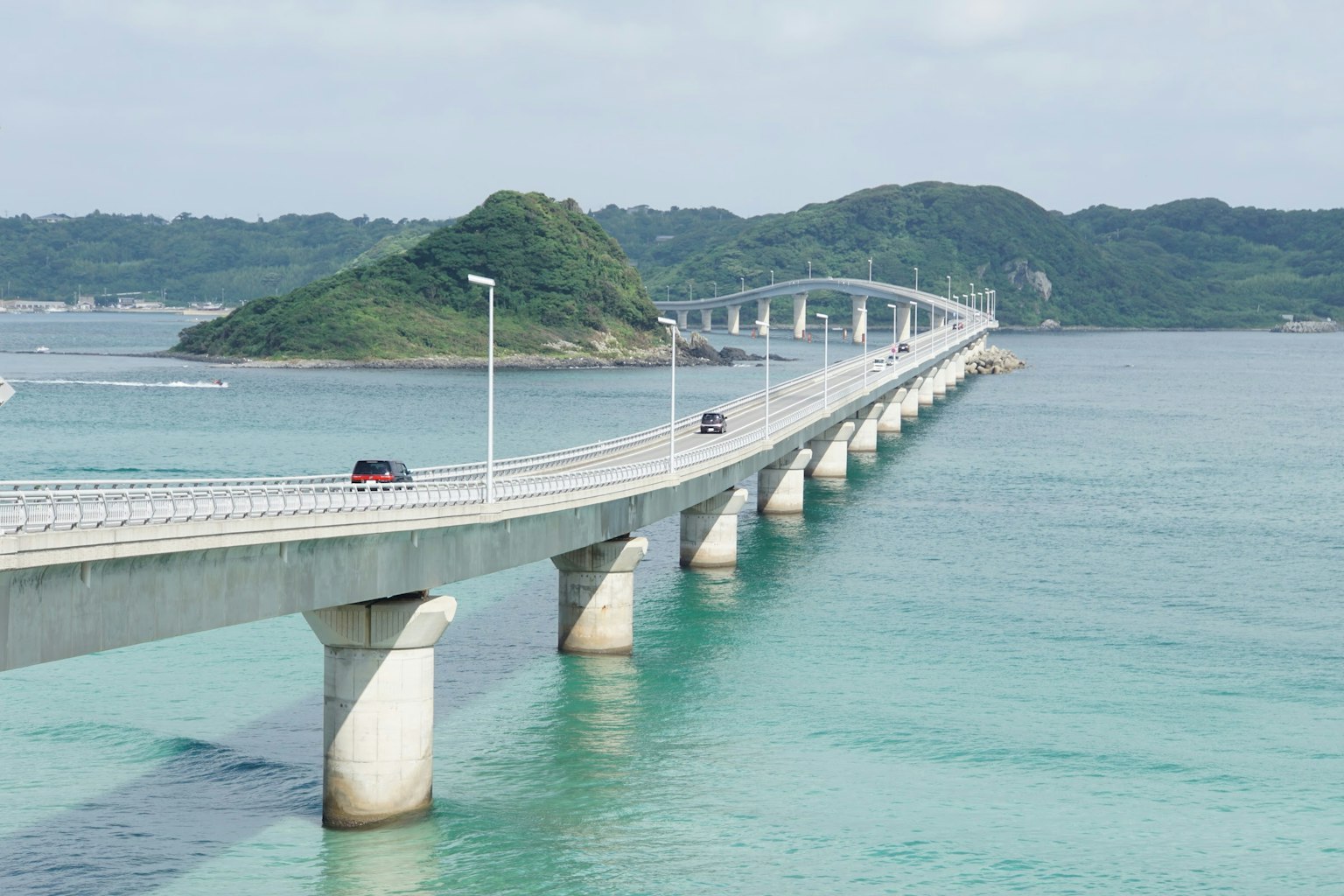 Un puente escénico que se extiende sobre aguas turquesas con una isla verde al fondo