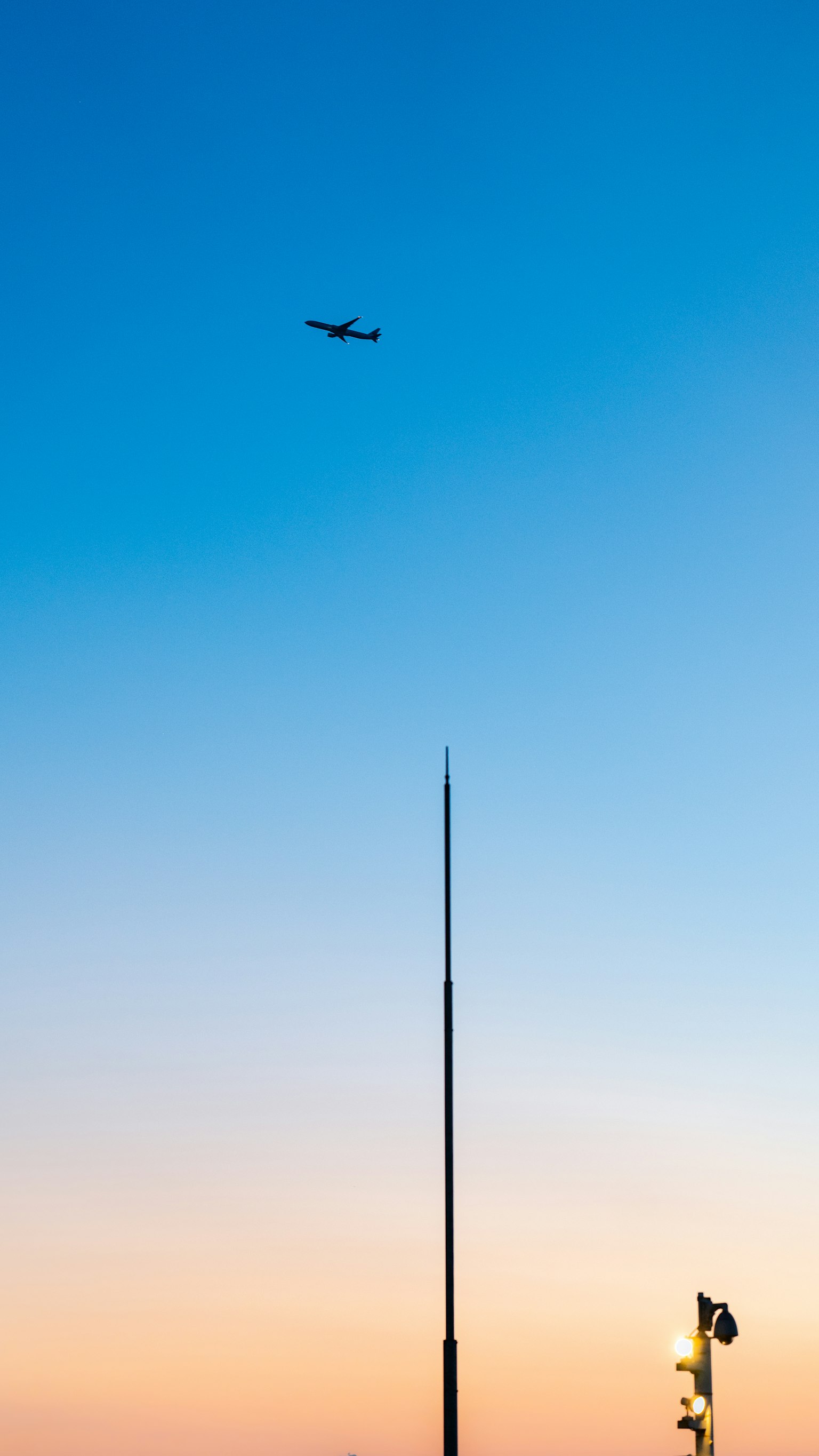 푸른 하늘에 나는 비행기와 높은 안테나의 실루엣