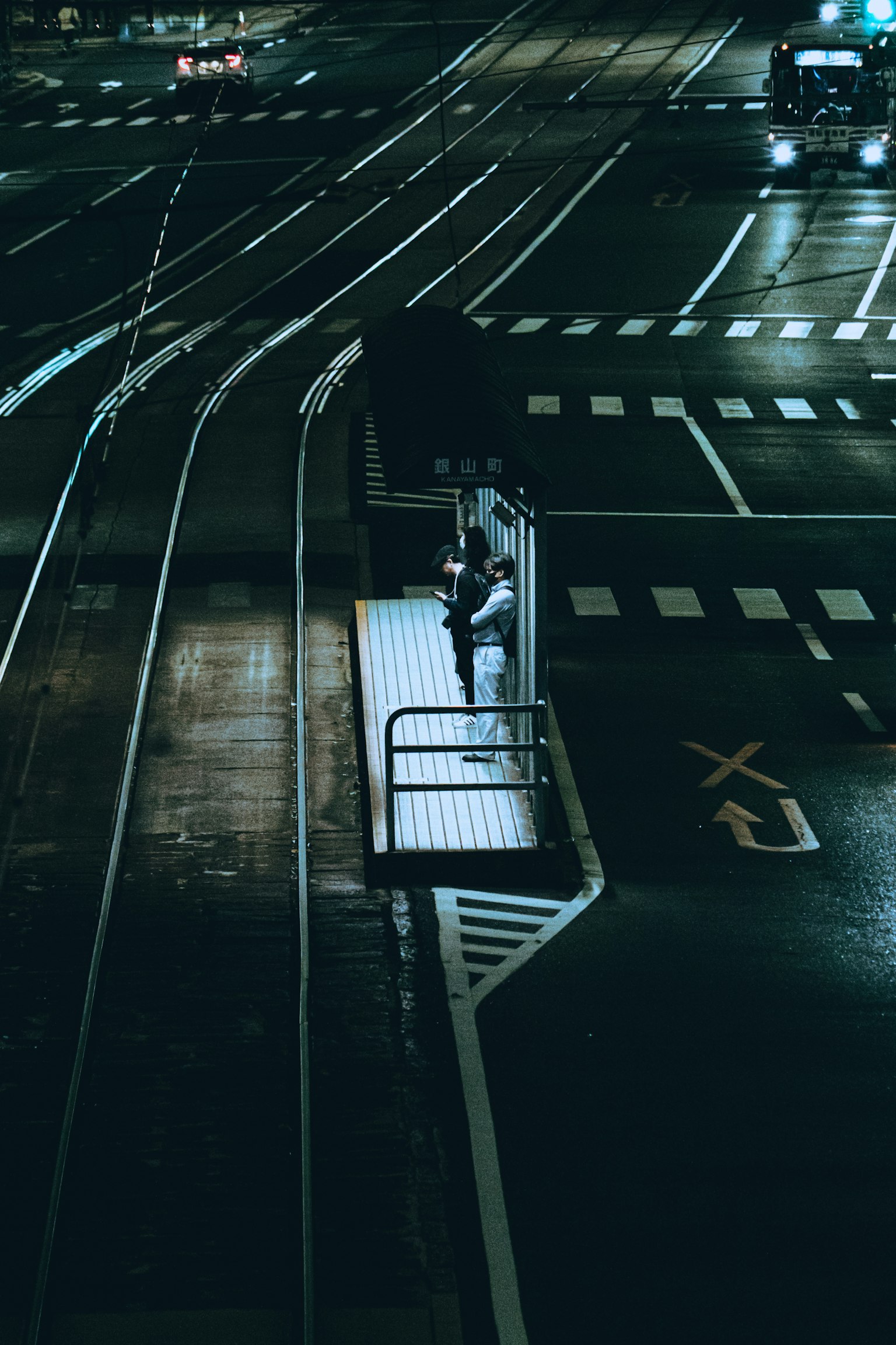 夜の街角で待つ人々と交差する線路