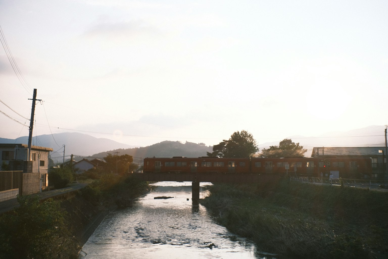 Scenic view of a river and bridge with mountains in the background during soft evening light