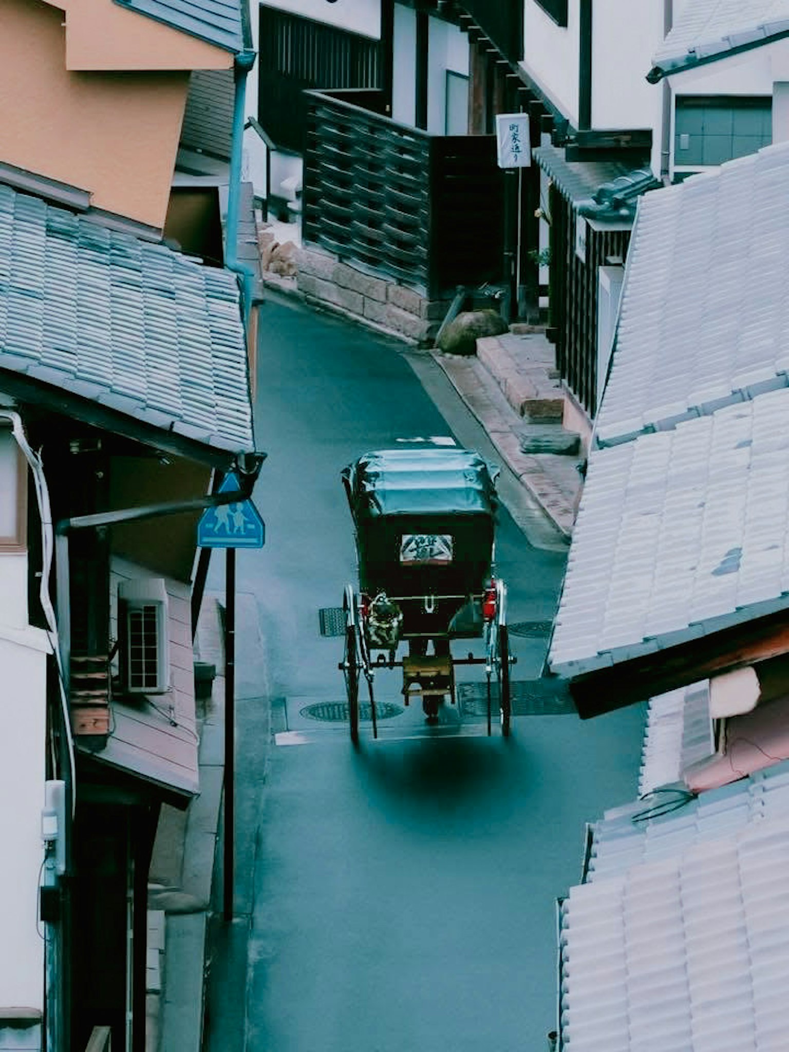 狭い路地を進む人力車と伝統的な日本の家々