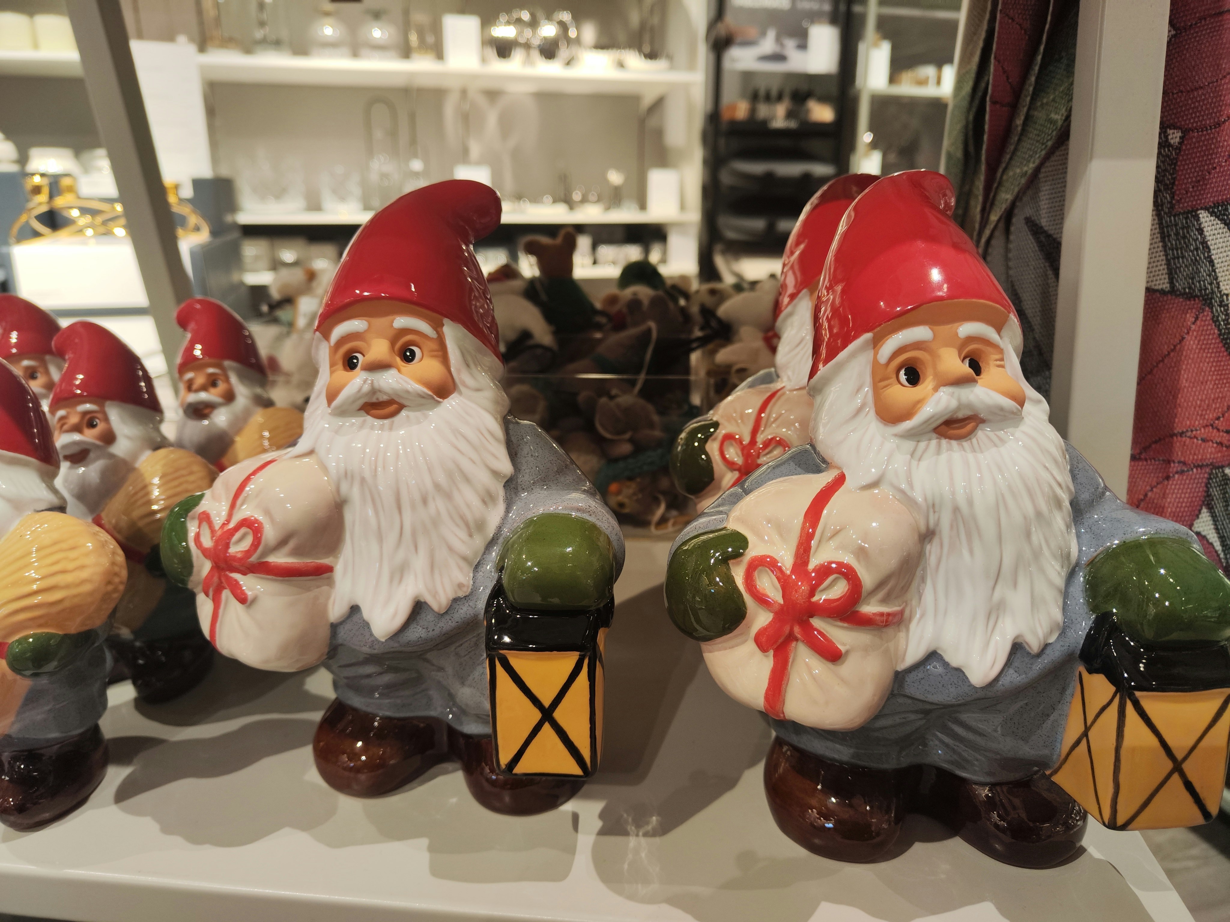 Deretan figur Santa merah dengan motif alat musik di etalase toko