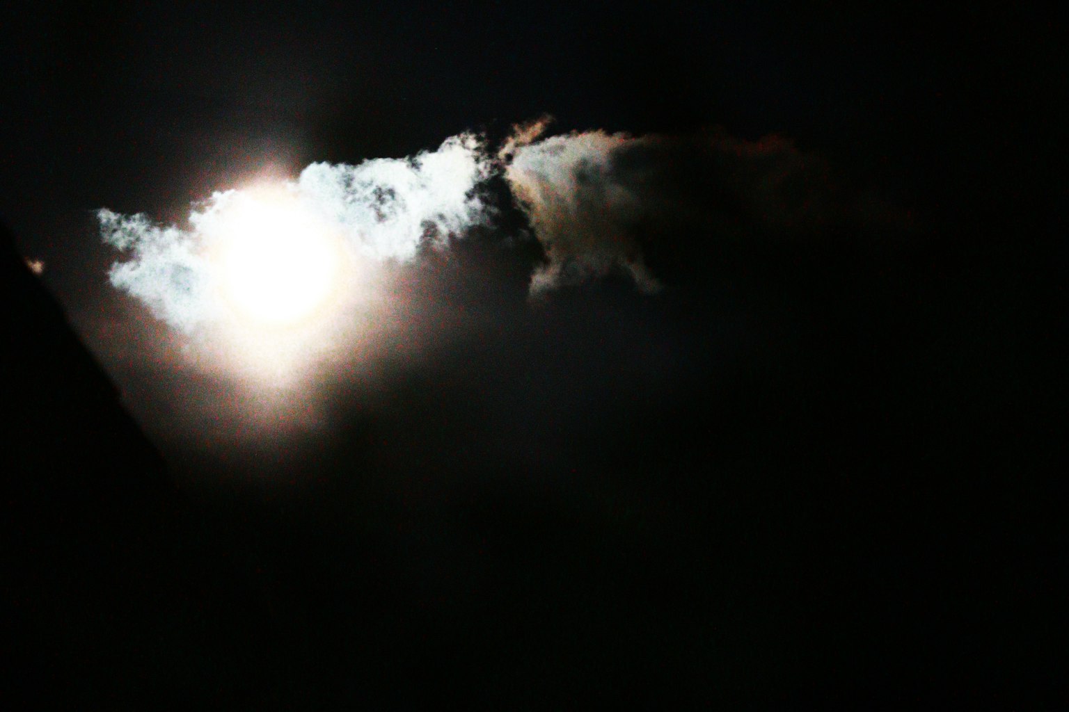 Bright light surrounded by clouds against a dark background