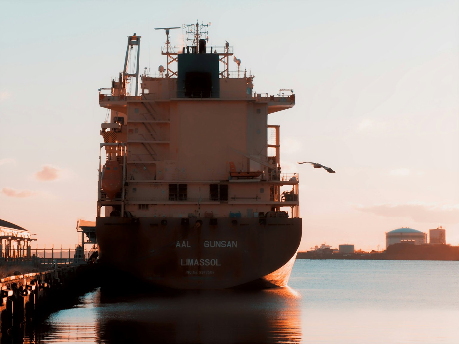 Navire cargo silhouetté contre le coucher de soleil avec de l'eau calme
