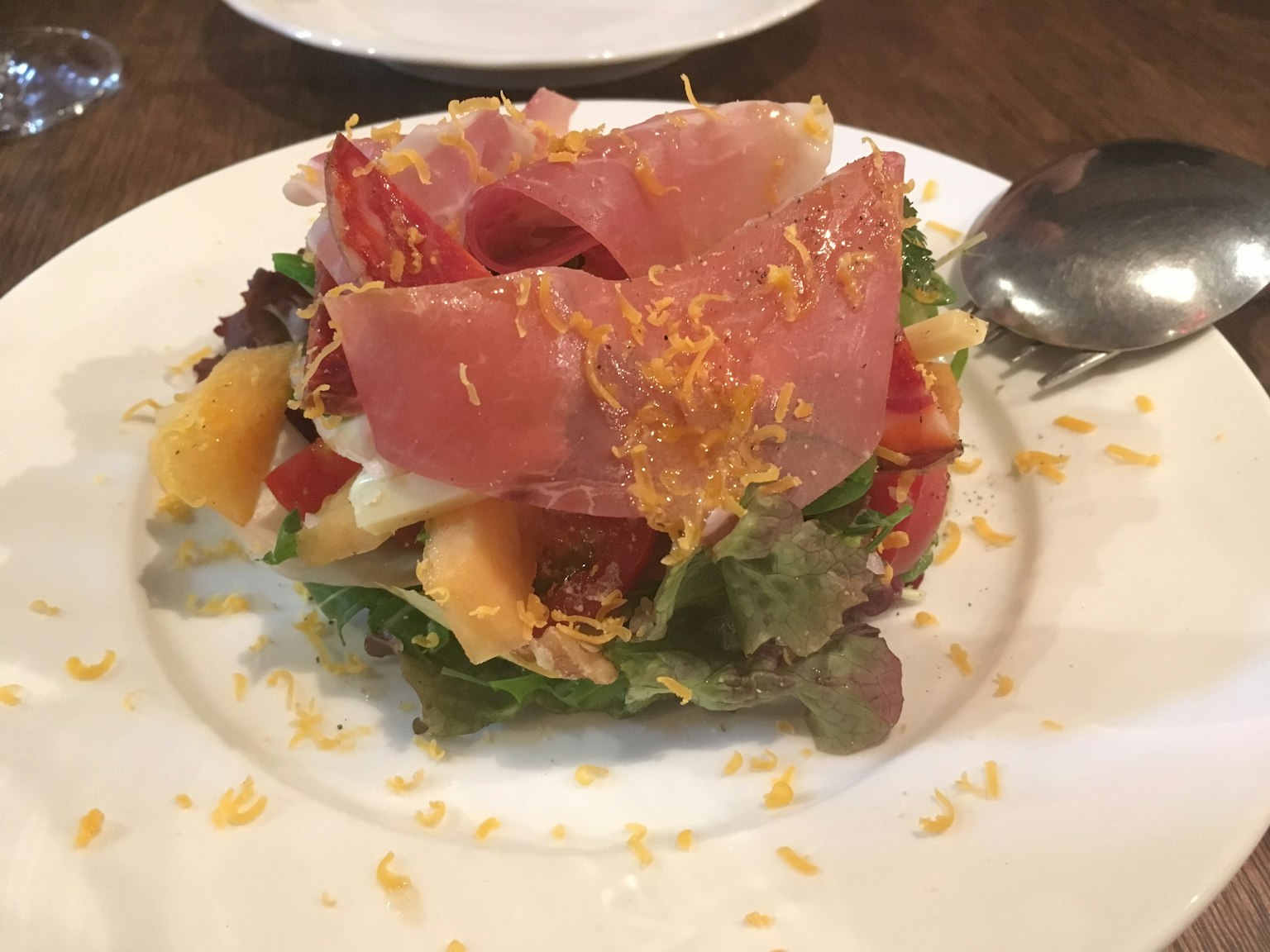 Salade avec des légumes colorés garnie de jambon et de fromage