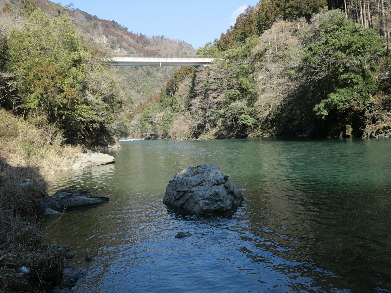 Vista panoramica del fiume con acqua verde e una roccia ponte sullo sfondo