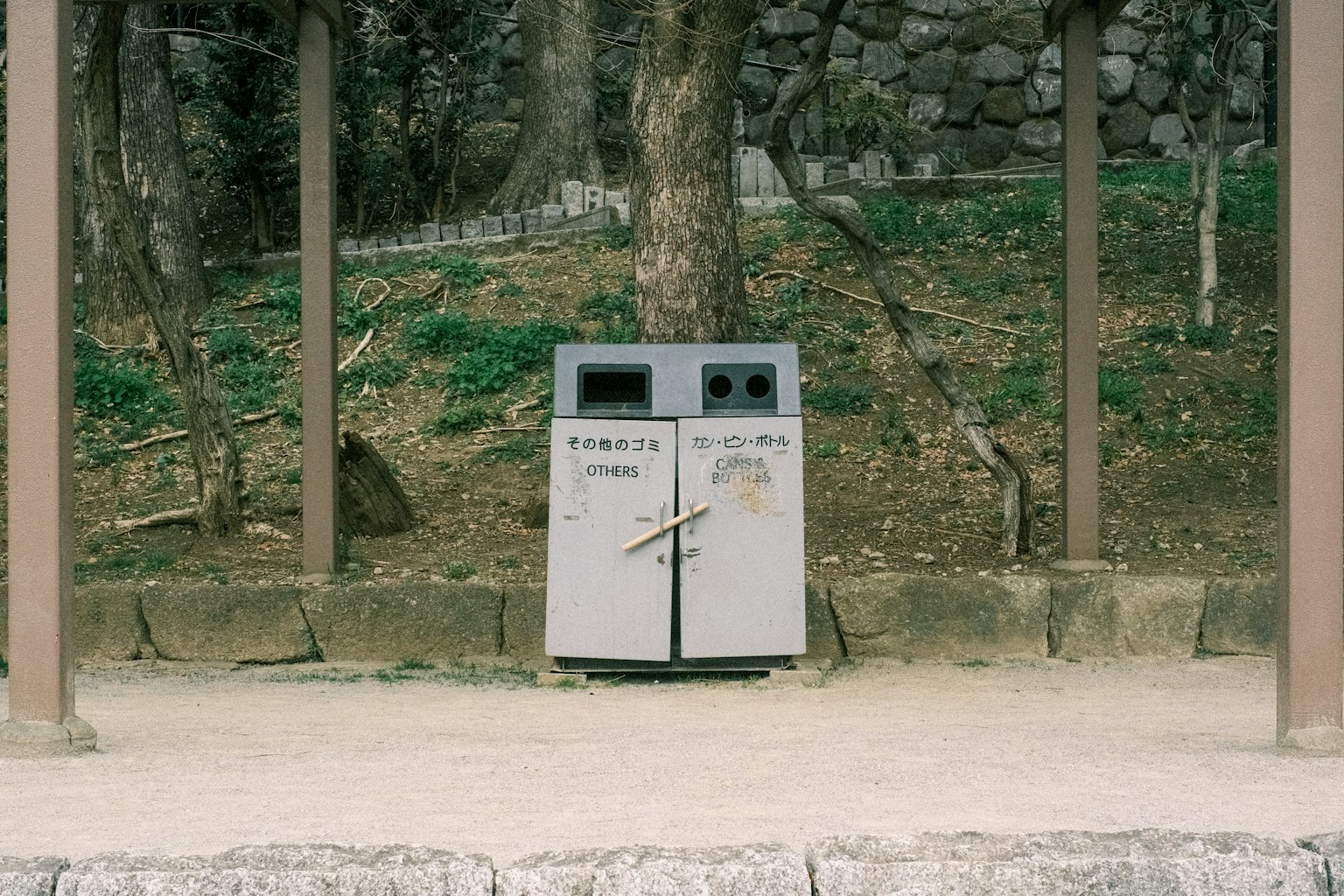 자연으로 둘러싸인 공원에 있는 두 개의 쓰레기통