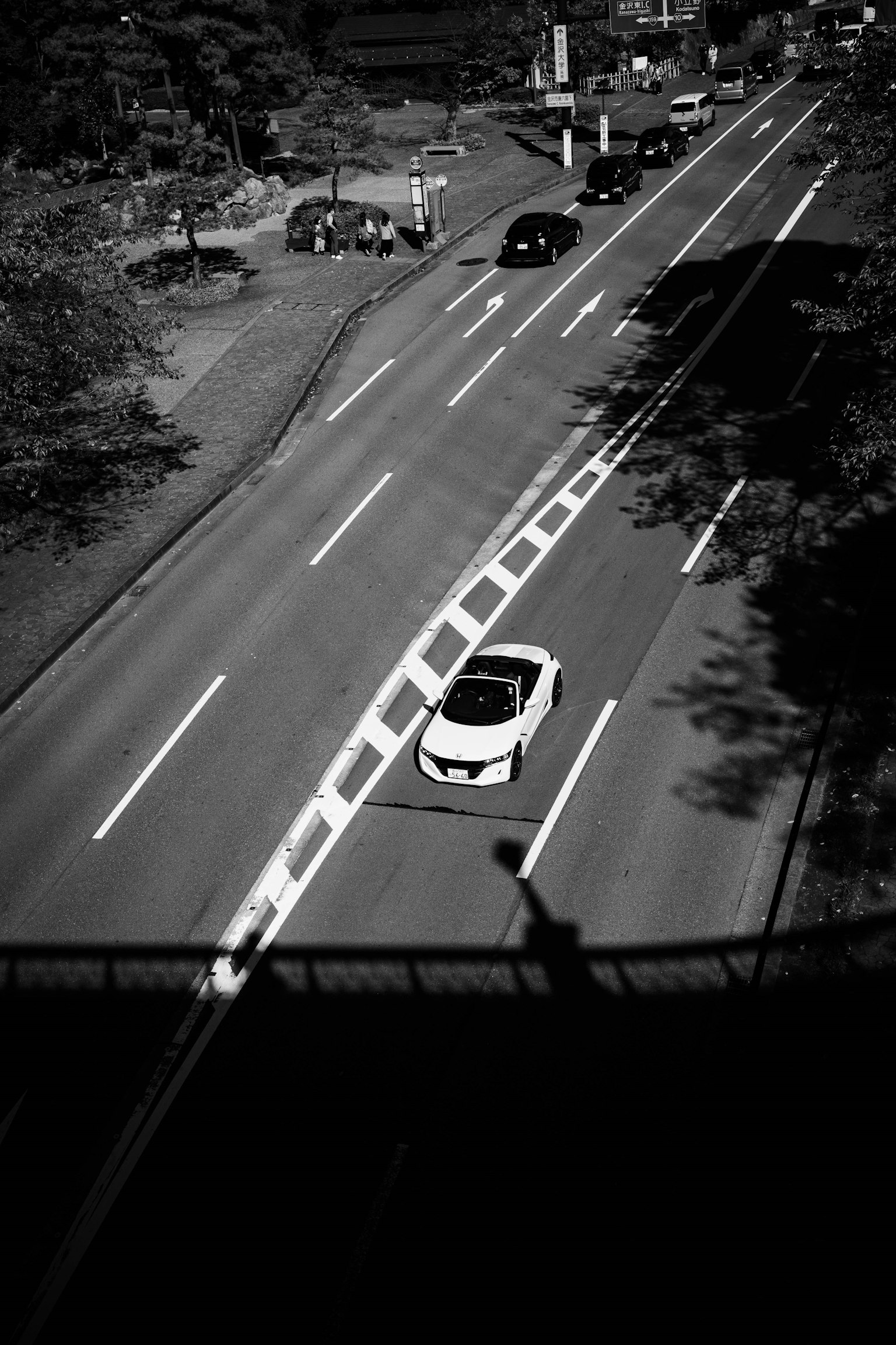 Escena de calle en blanco y negro con un coche y tráfico circundante