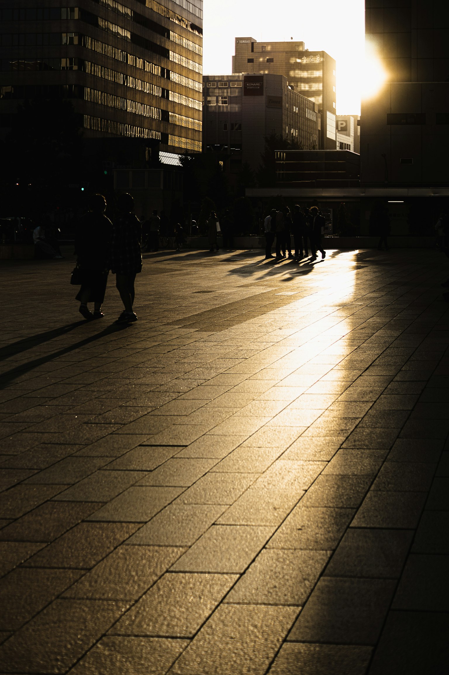 Silhouettes de personnes marchant sur une rue de la ville avec un coucher de soleil en arrière-plan