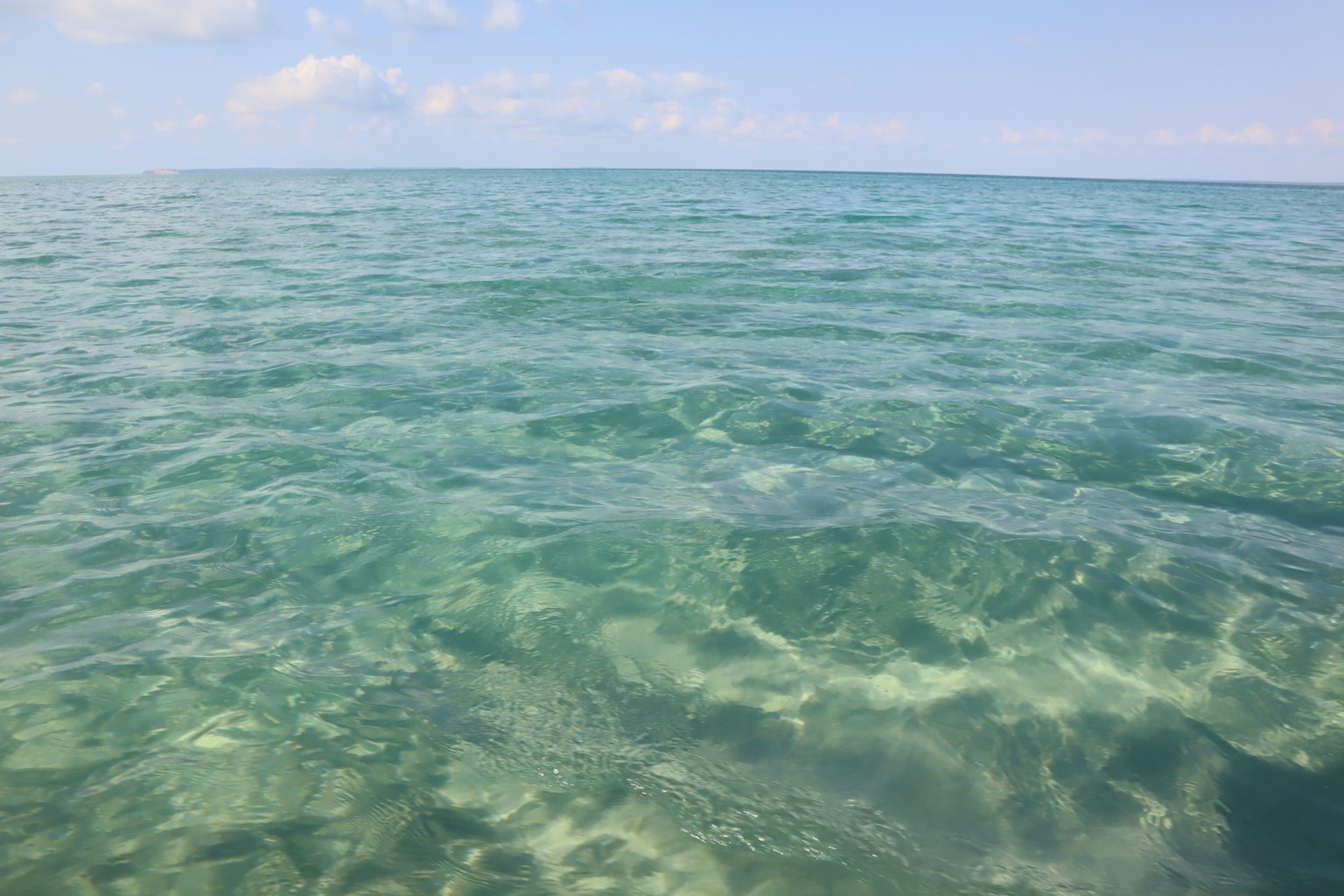 Acqua turchese chiara che ondeggia dolcemente sotto un cielo sereno