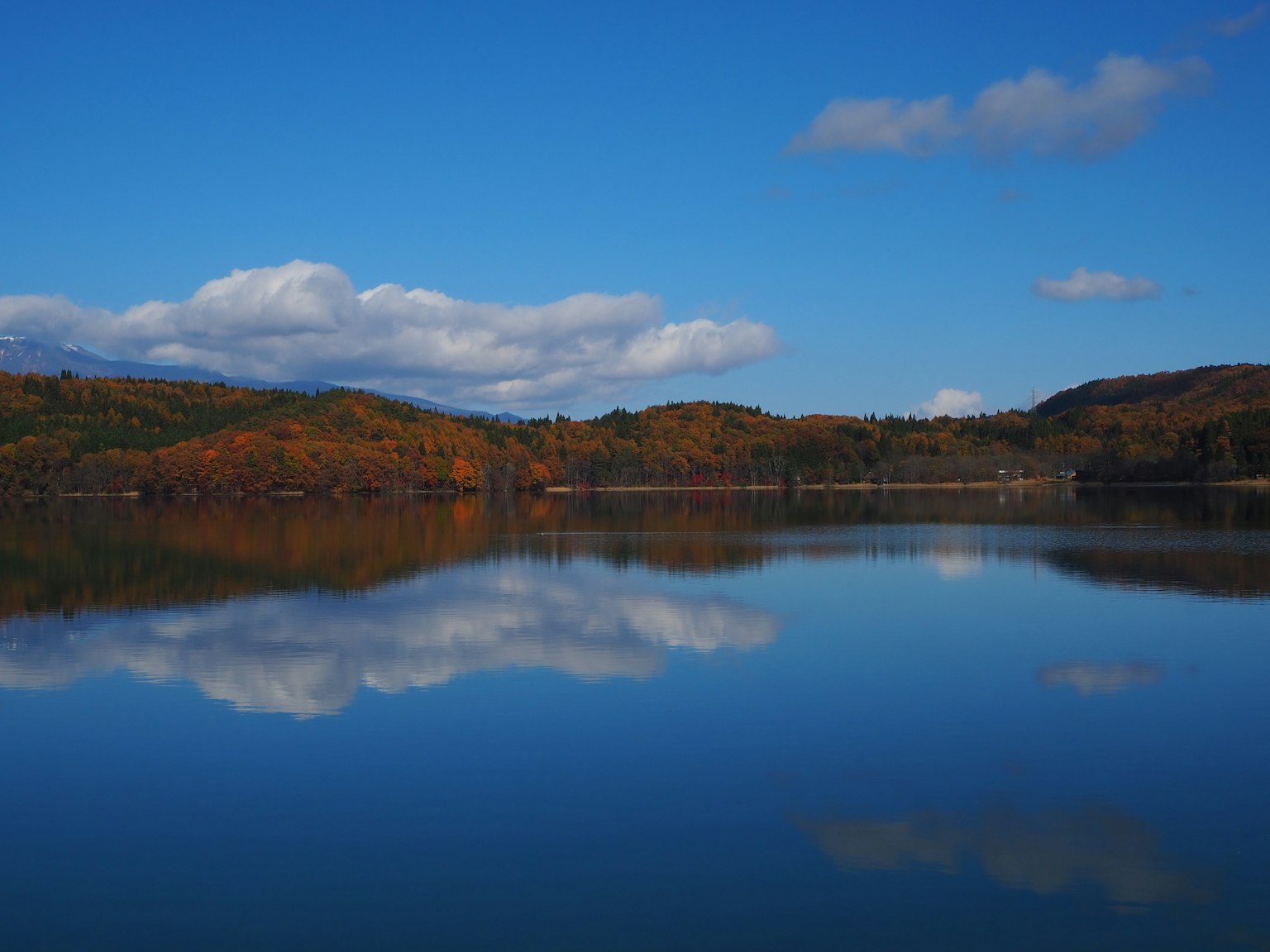 Lago tranquilo reflejando el cielo azul y las nubes