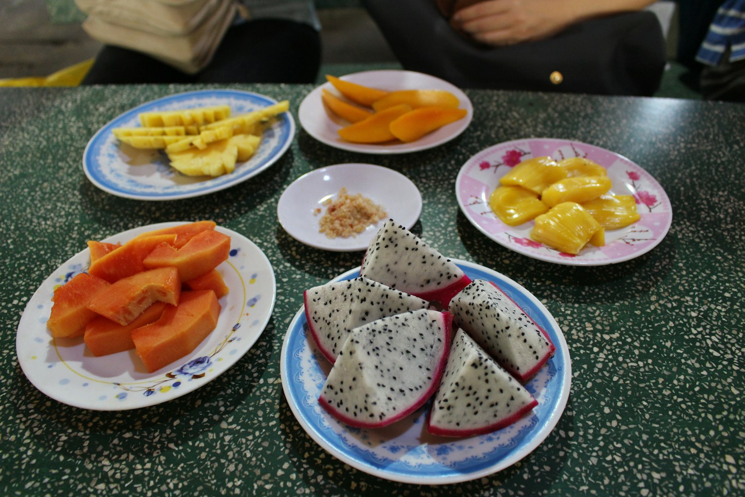 Piring berwarna-warni berisi berbagai buah diletakkan di atas meja