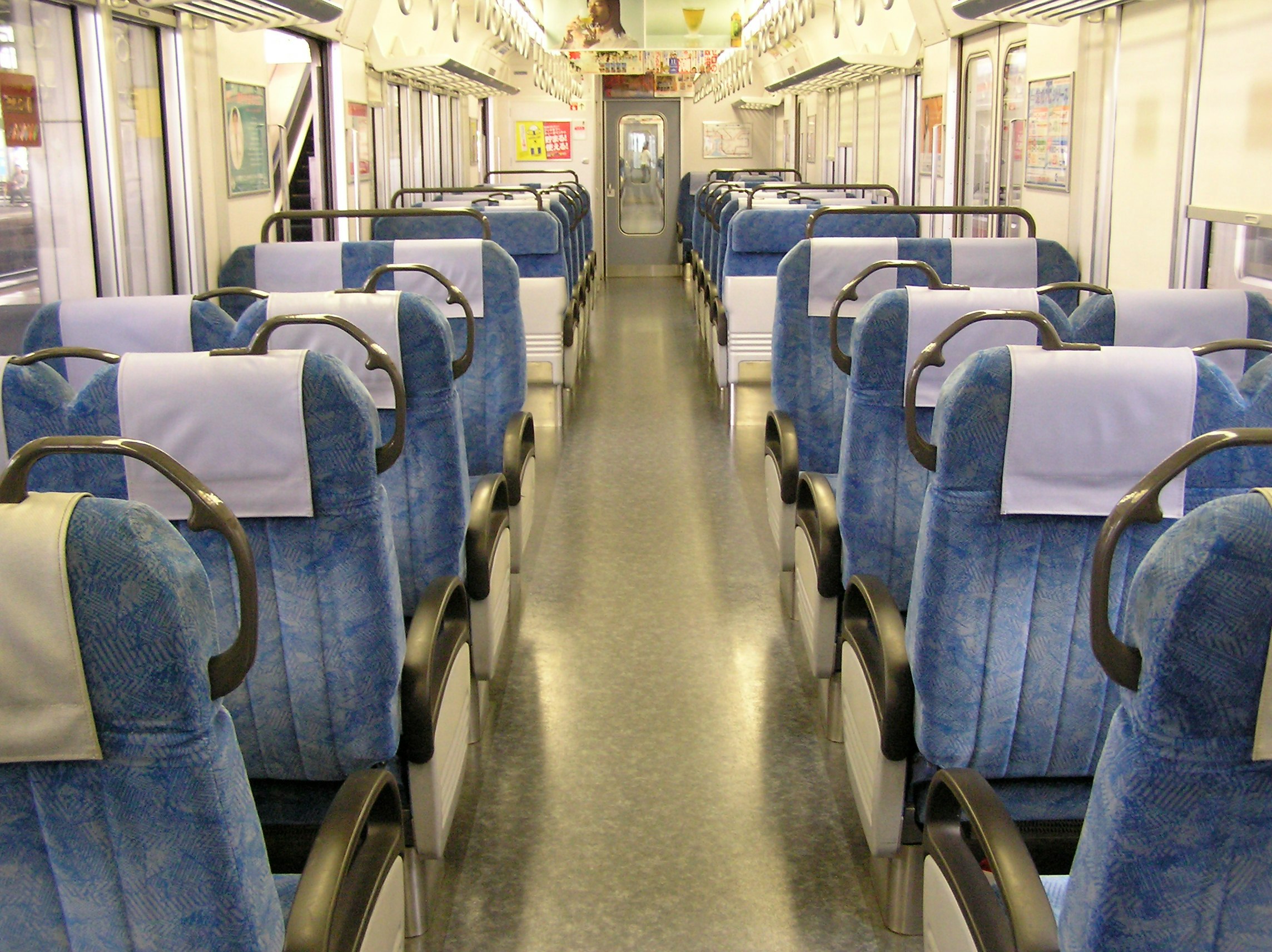 corridoio di un vagone ferroviario con file di sedili blu