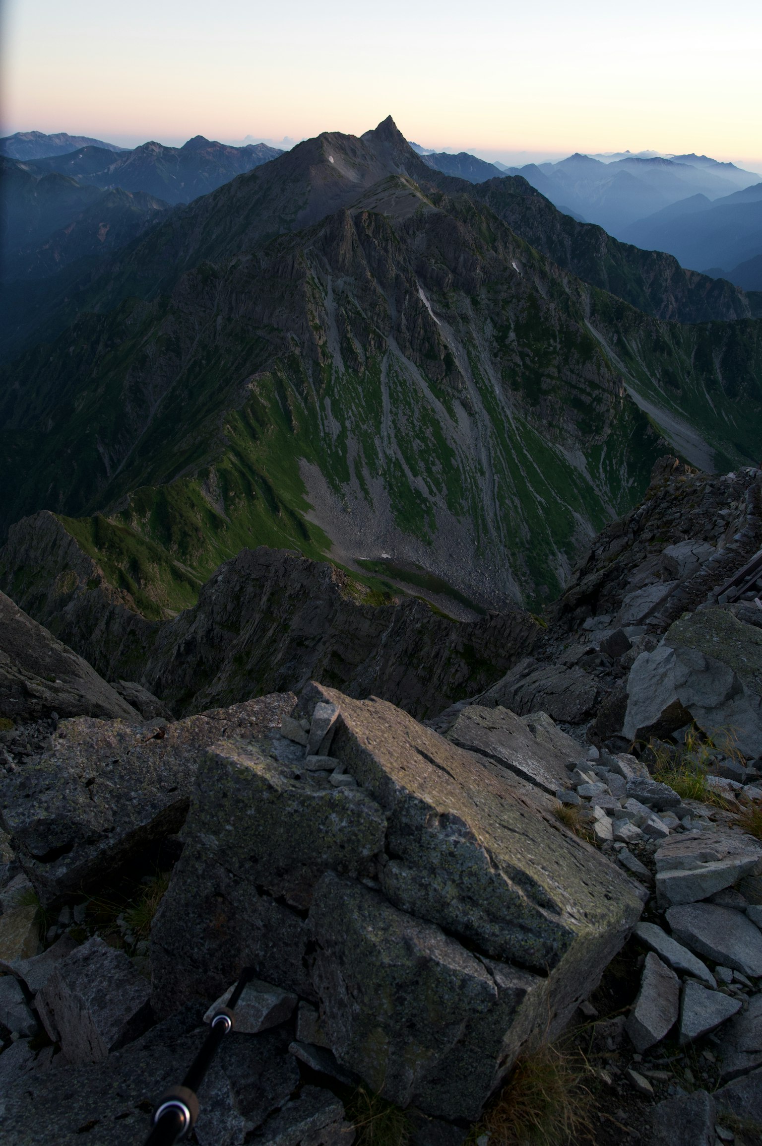 从山顶俯瞰的戏剧性山景，岩石和绿色坡道