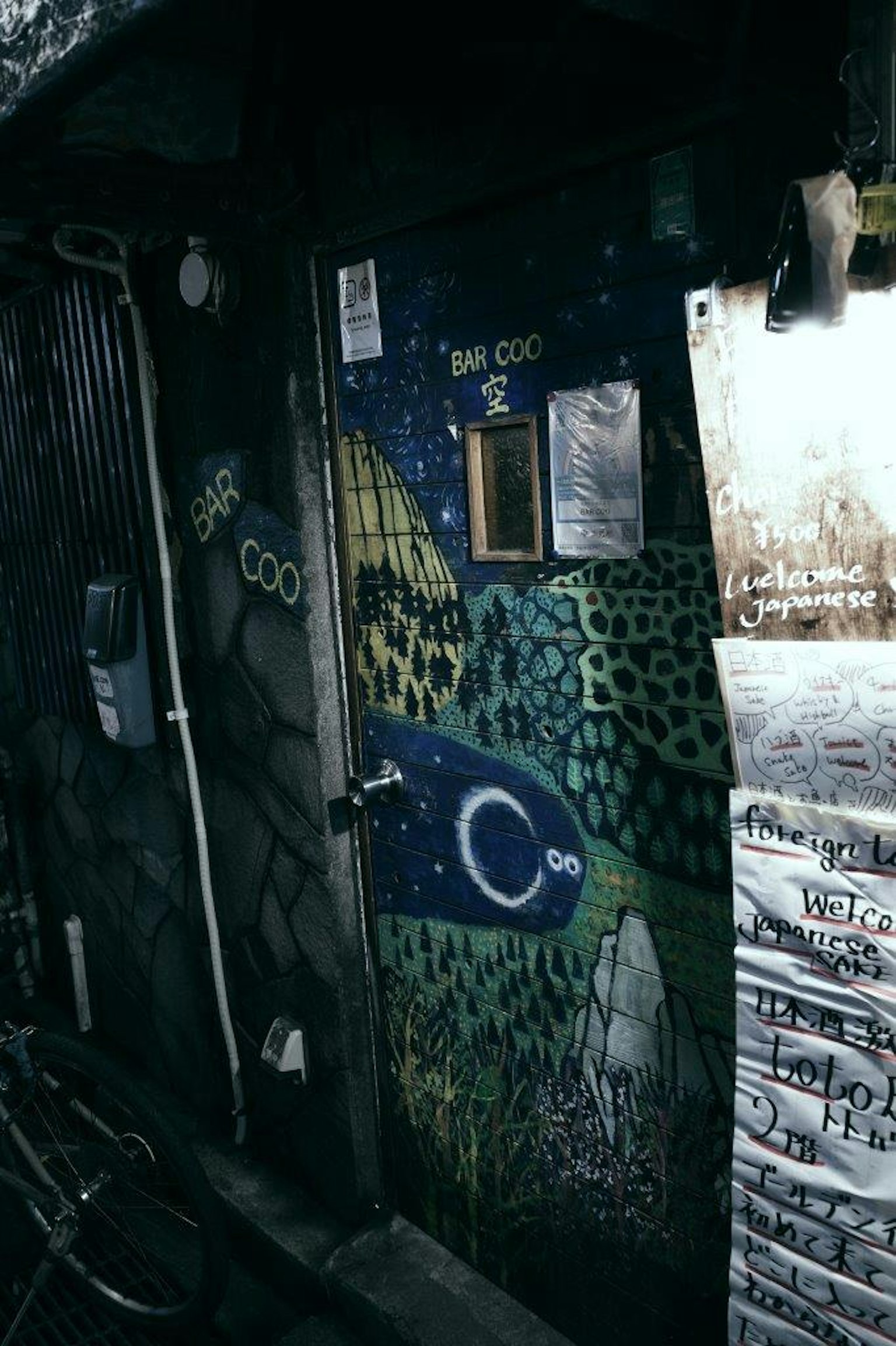 Una pared con una puerta decorada con arte abstracto verde y azul
