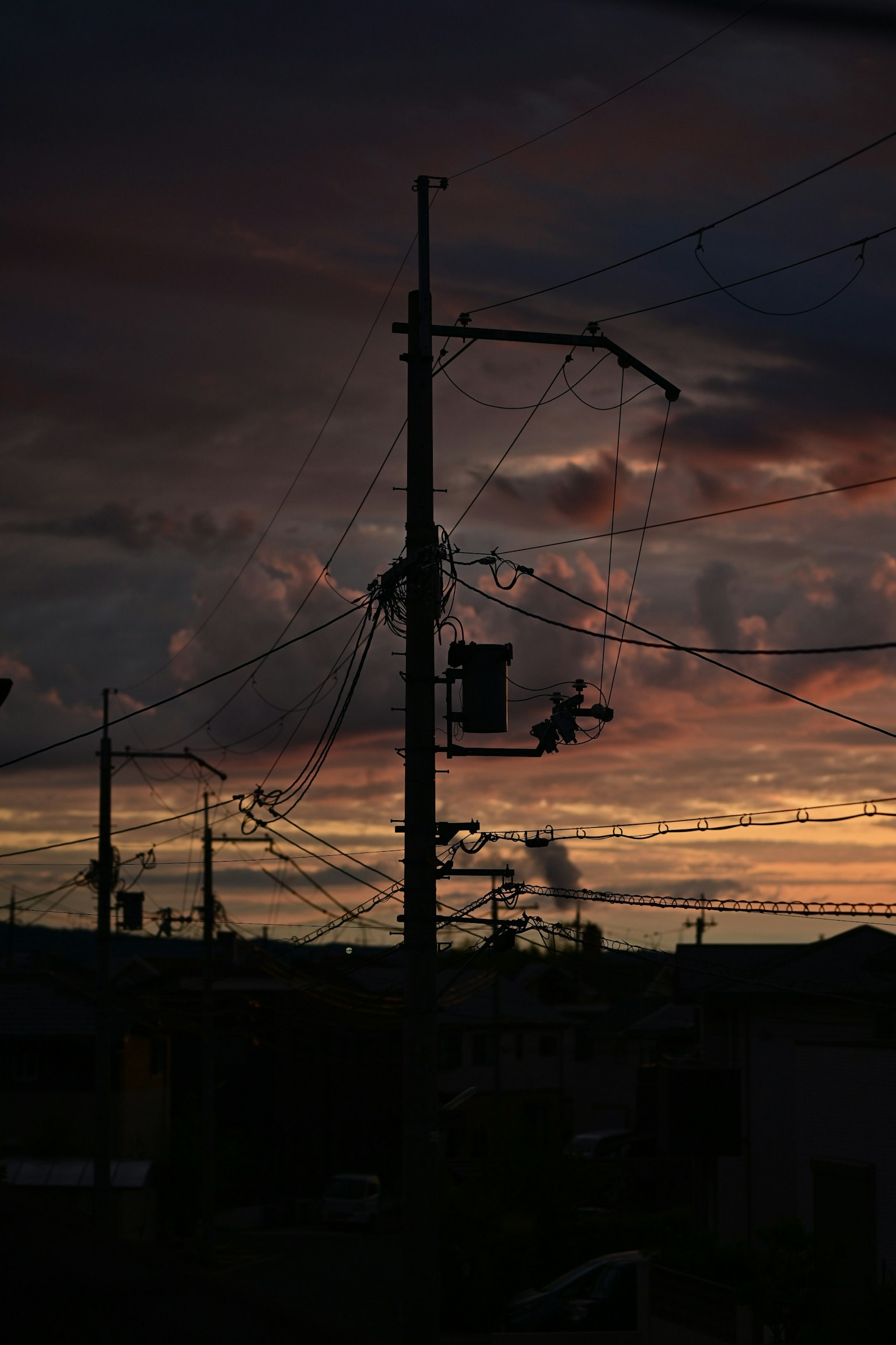 Silhouette di pali elettrici e cavi contro un cielo al tramonto
