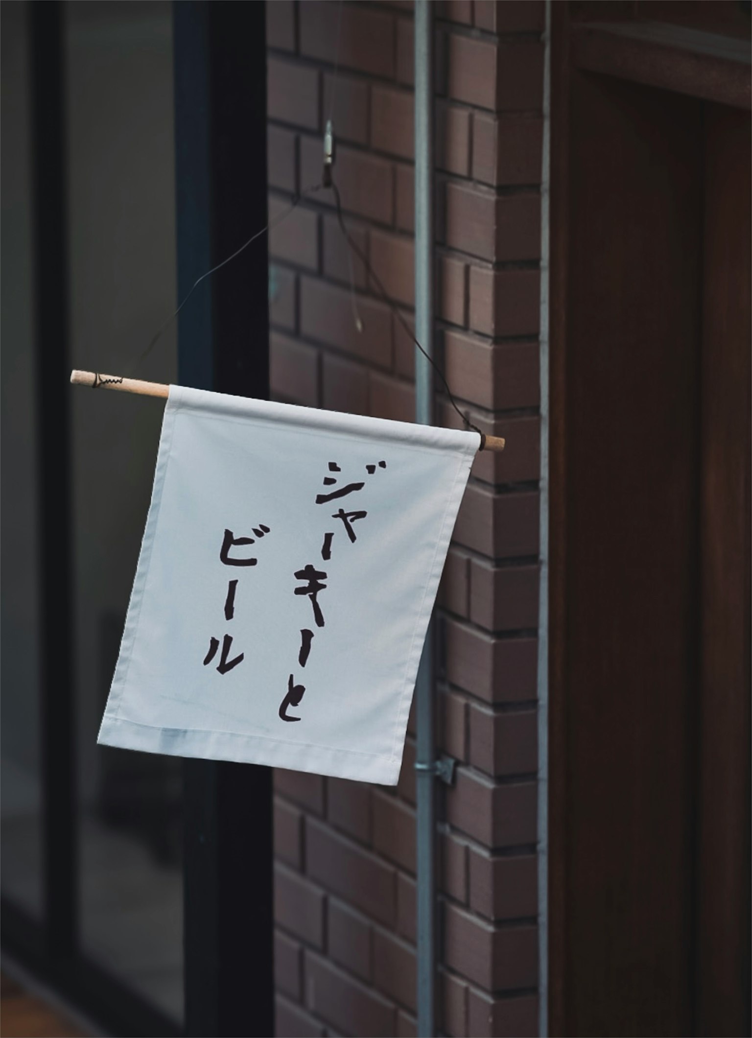 Weißes Banner mit japanischem Text, das an einer Backsteinmauer hängt