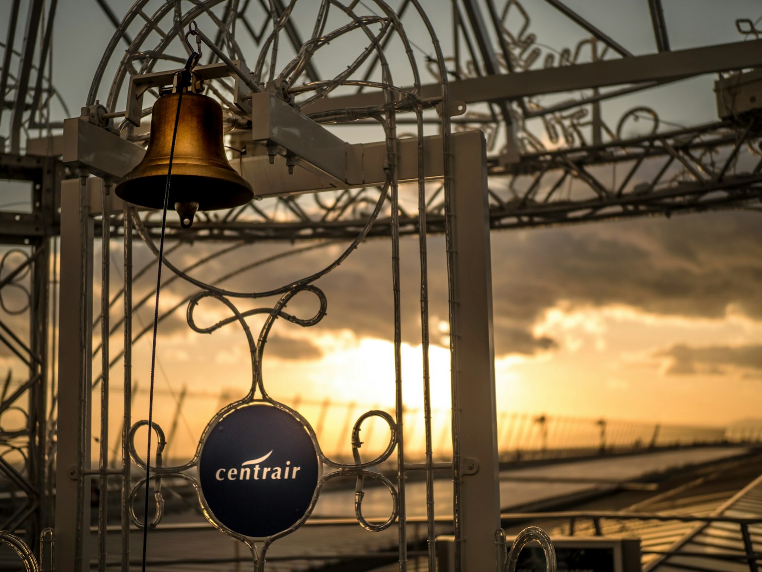 Glocke und Centrair-Schild vor einem Sonnenuntergang