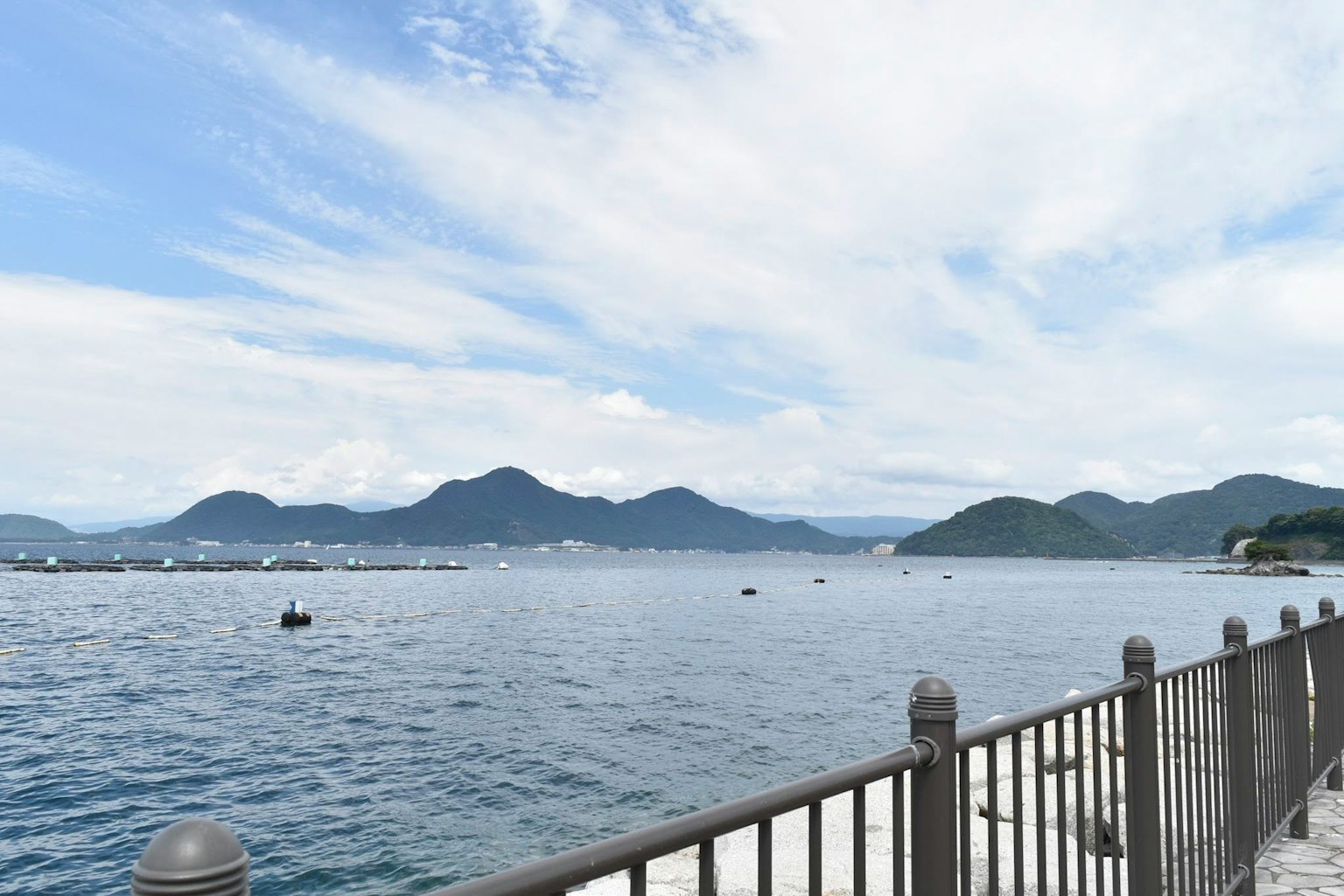 Malersicher Blick auf das blaue Meer und die Berge entlang eines Zauns