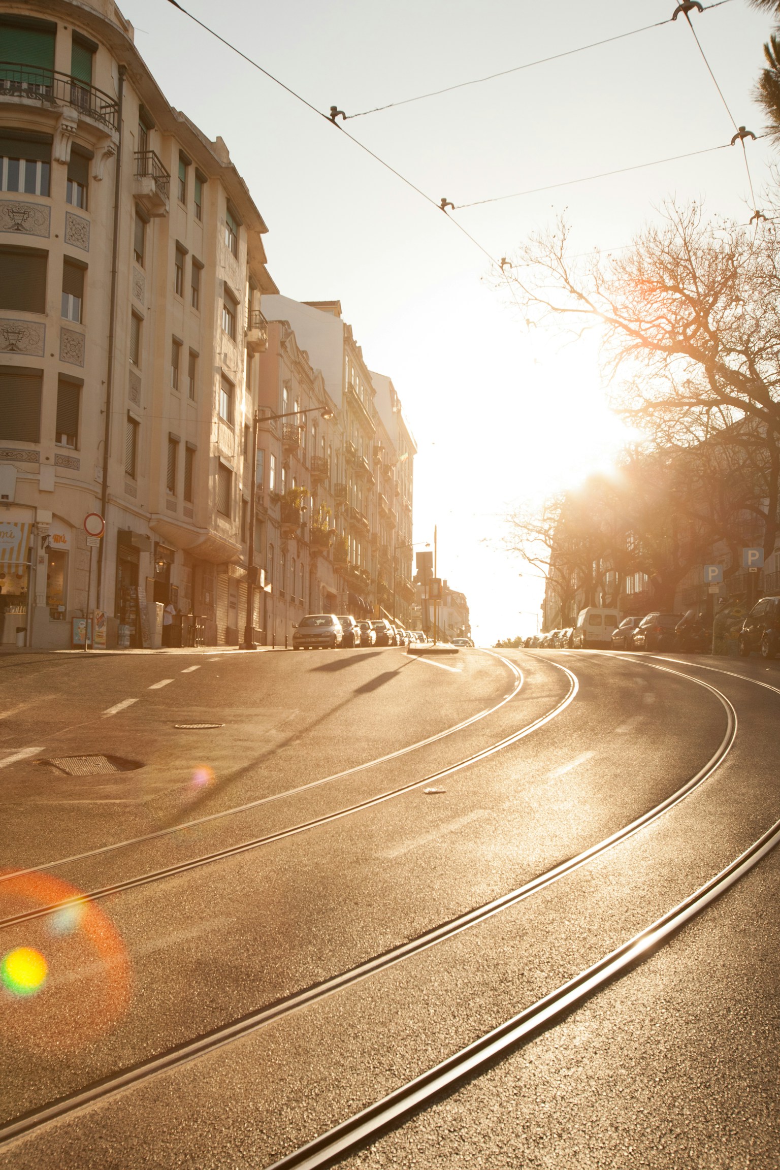 Scène de rue avec le soleil se couchant sur des rails de tram courbés