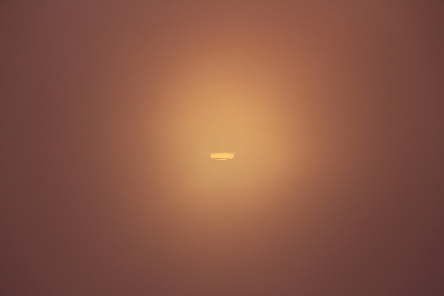 Bild mit einem kleinen weißen Punkt, umgeben von orangefarbener Licht in der Mitte