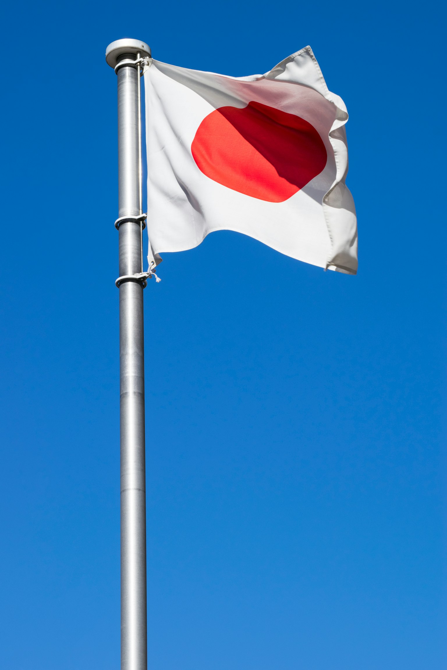 Japanese national flag waving on a pole against a blue sky
