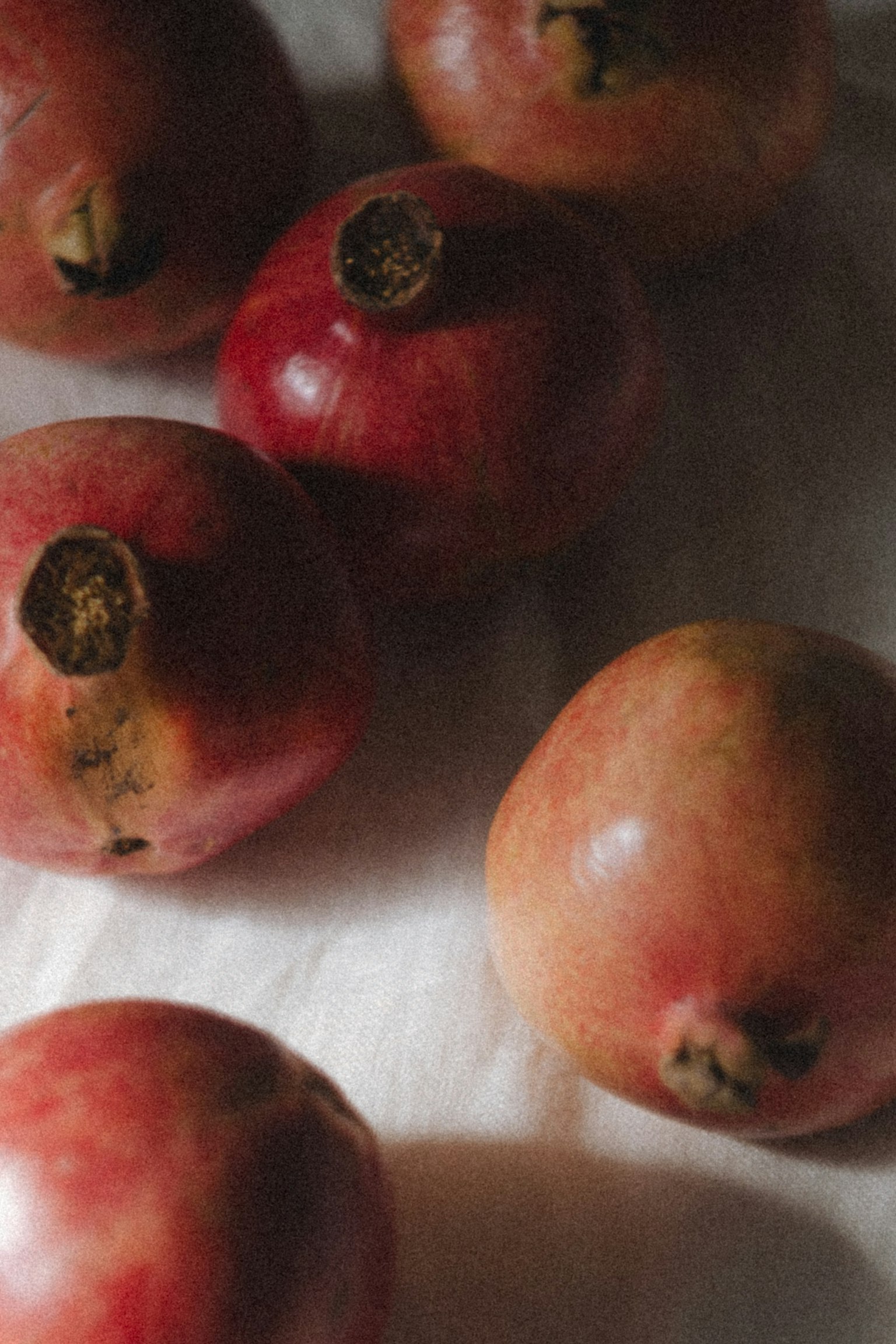 赤いザクロが白い布の上に置かれている写真