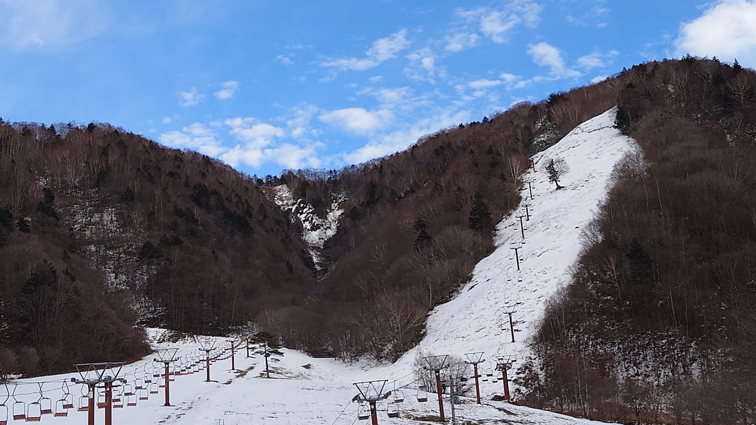 Paisaje montañoso cubierto de nieve con cielo azul telesillas y pistas visibles