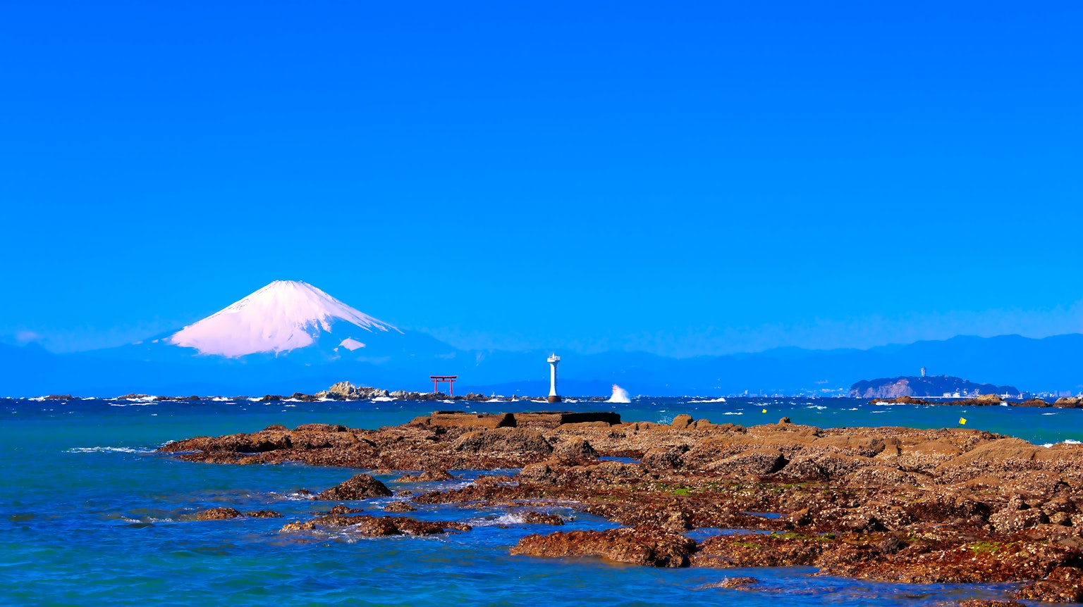 Vista costiera con il Monte Fuji sotto un cielo blu chiaro