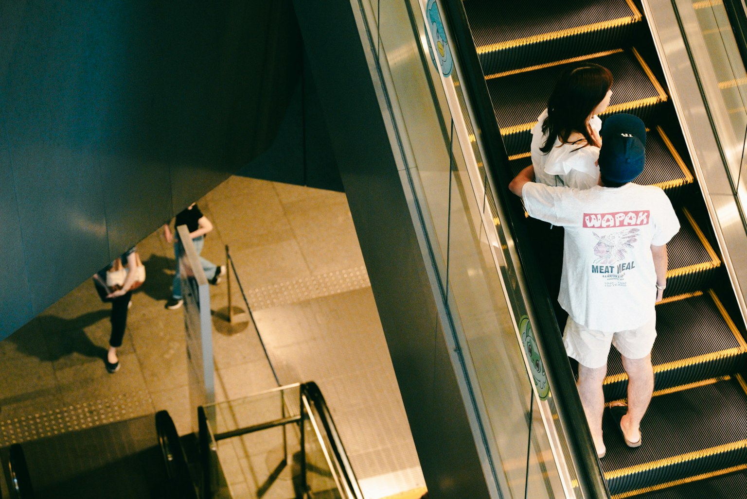 A scene of people using an escalator with a young couple and other pedestrians visible