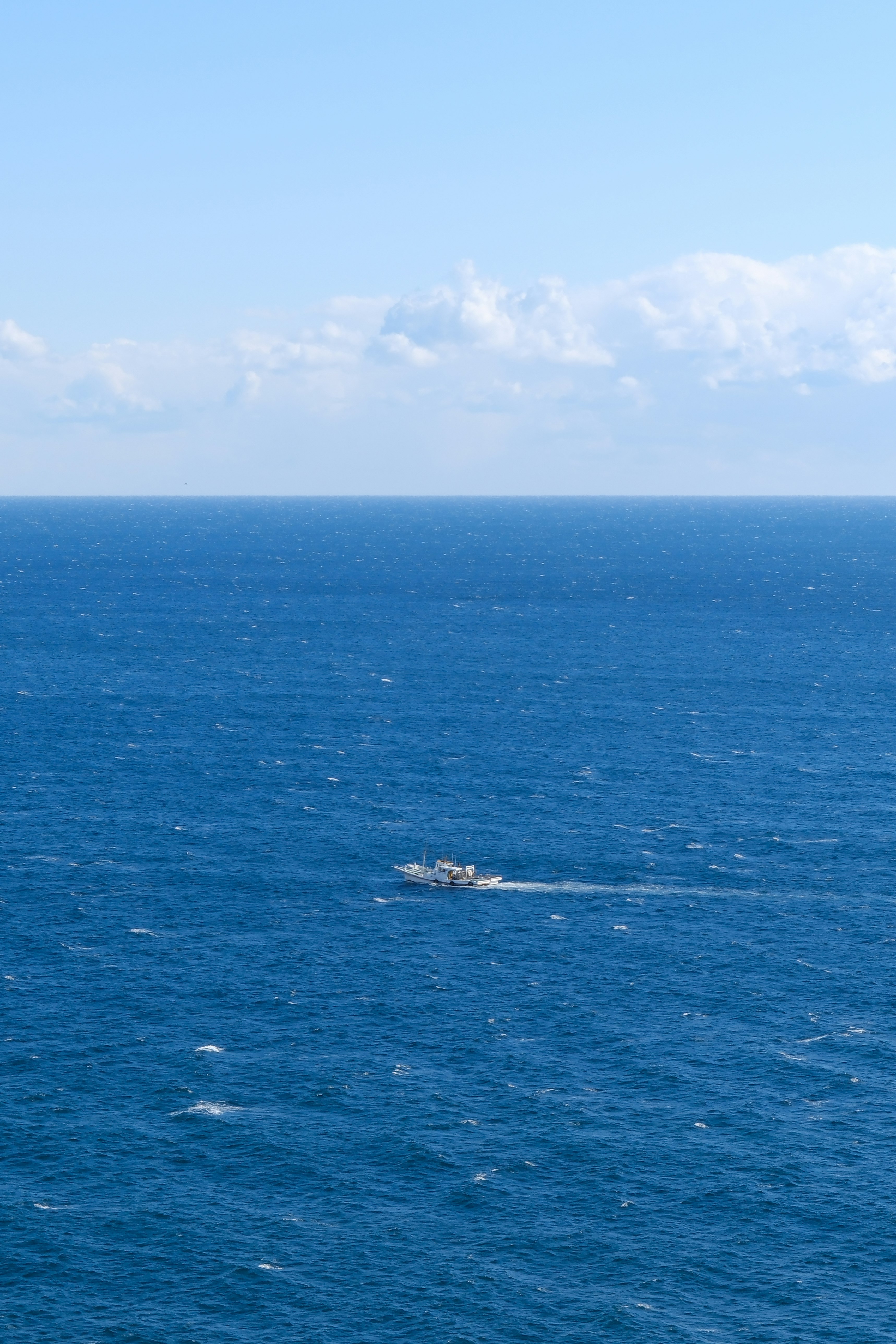 青い海原に浮かぶ小さな船影