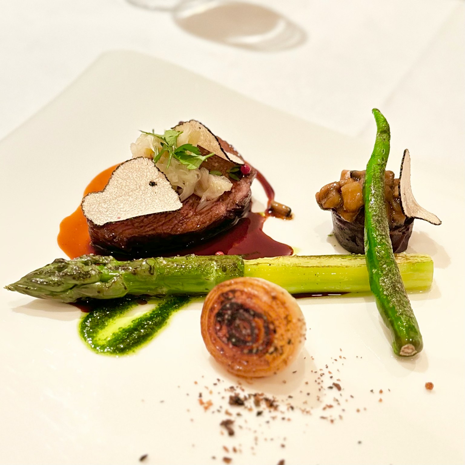 Présentation de plat gastronomique avec du bœuf et des asperges garni de truffe et de sauce
