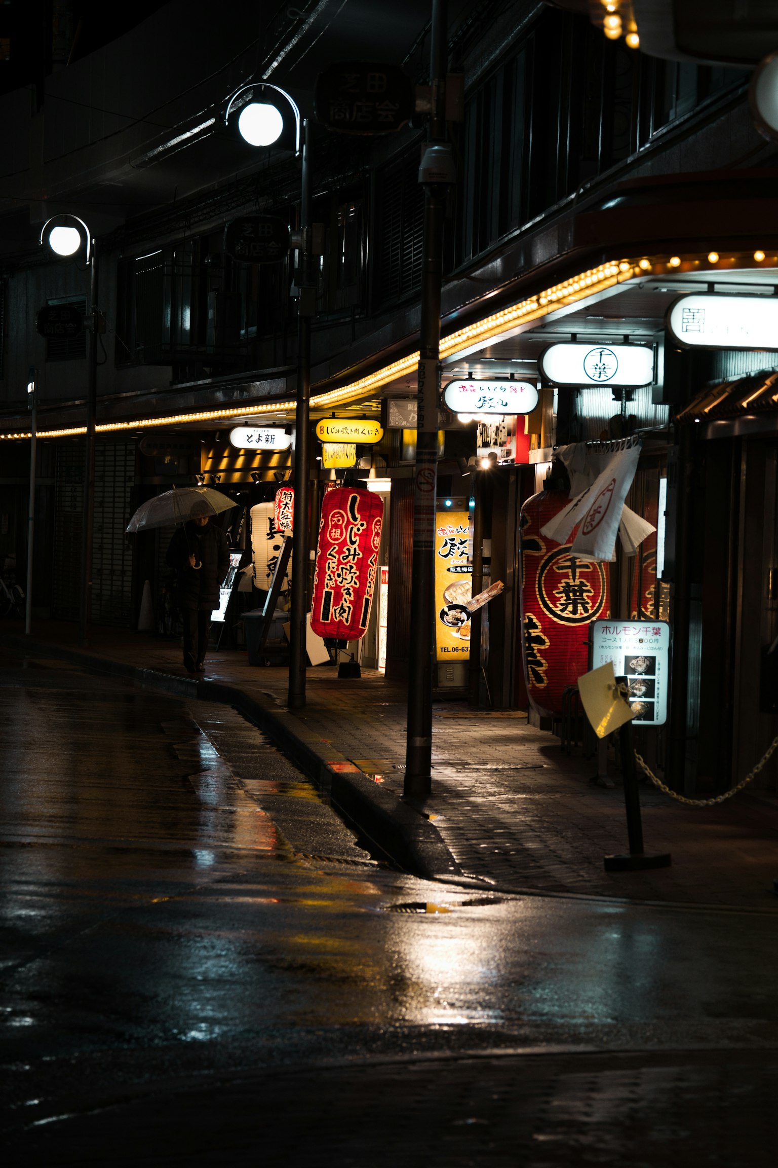 雨に濡れた街の通りにある飲食店の看板と照明