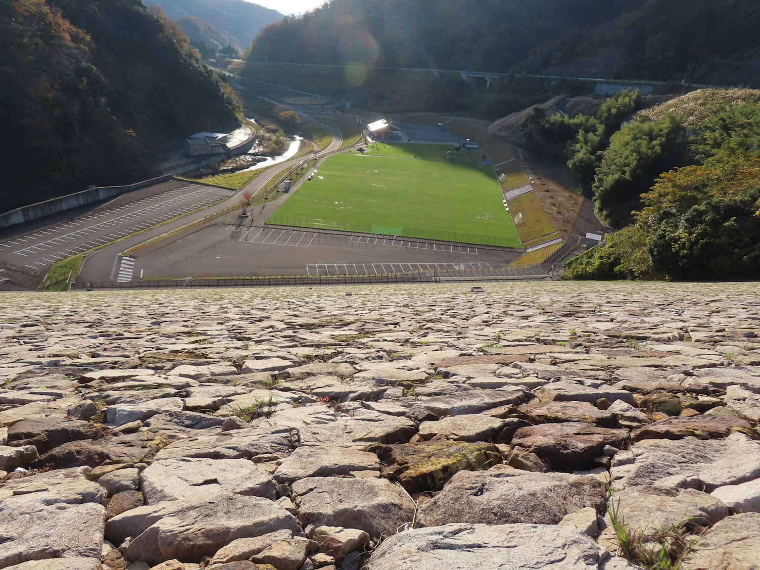 Vista da un ledge roccioso su un campo da calcio verde e la natura circostante