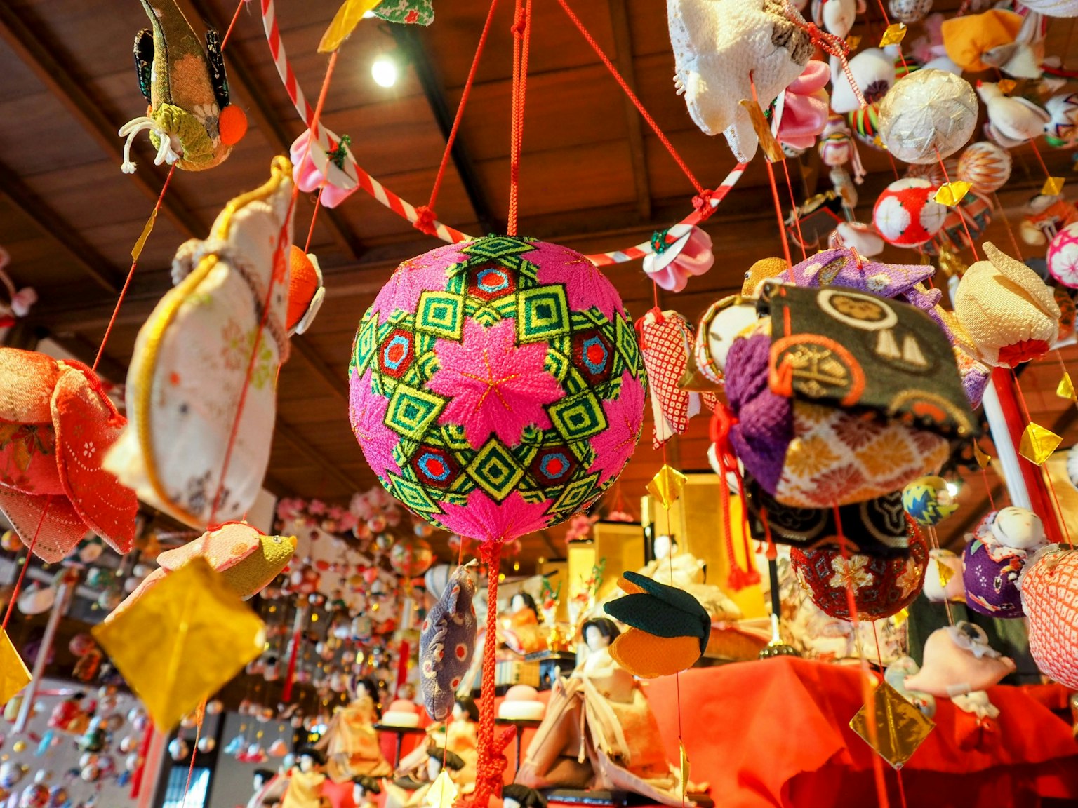 Muñecas coloridas colgadas en el interior con una bola decorativa rosa en el centro rodeada de muñecas y adornos japoneses tradicionales