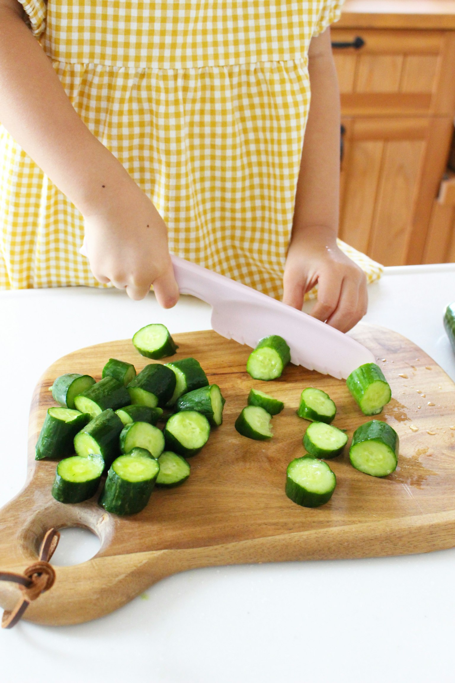 Child cutting cucumbers on a wooden cutting board