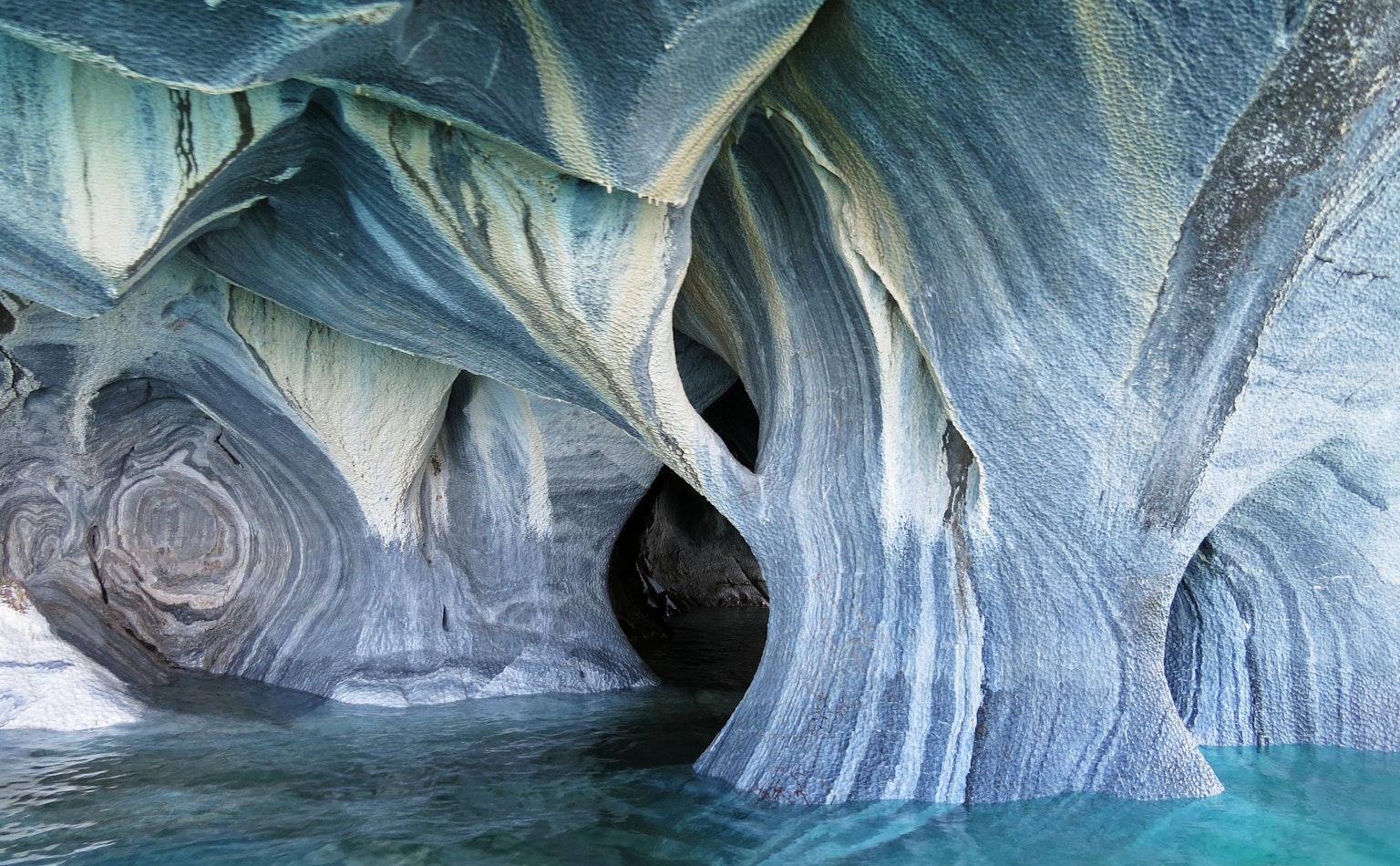 Motifs et formes uniques des grottes de marbre reflétés dans l'eau bleue