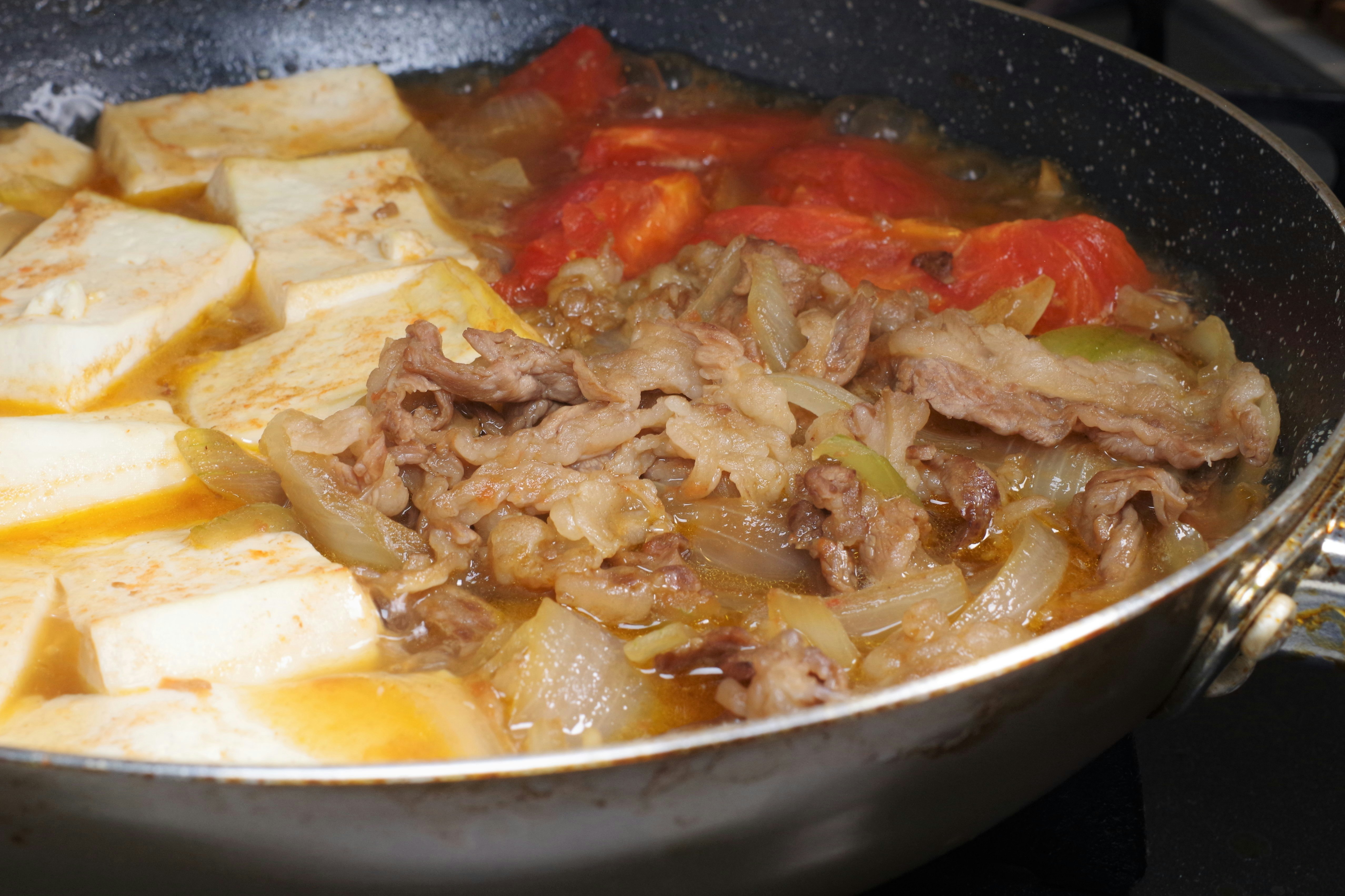 フライパンで煮込む肉と野菜の料理