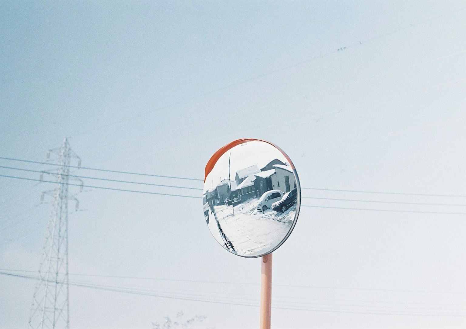 Reflective mirror under blue sky with power lines