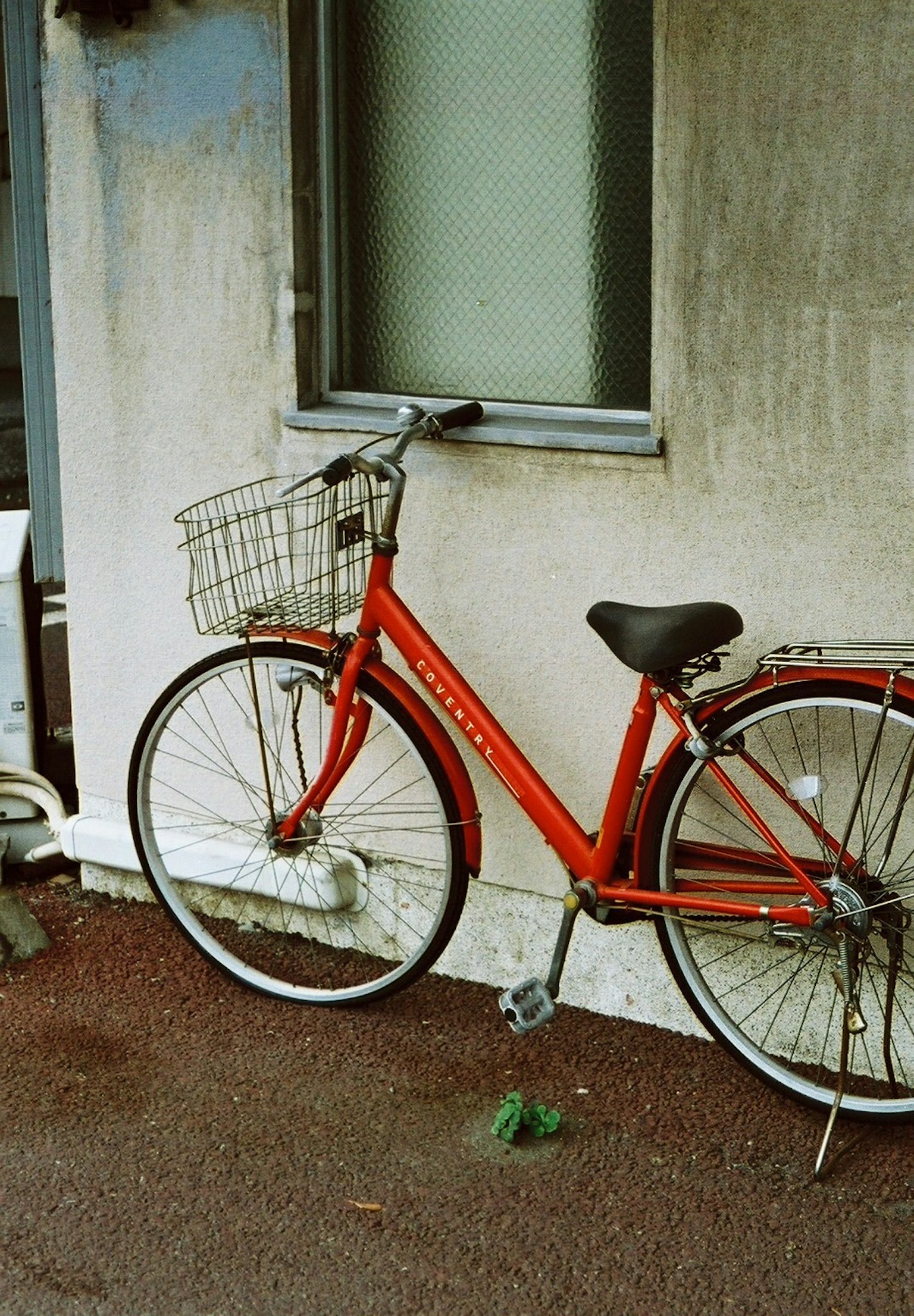 Red bicycle parked near a wall