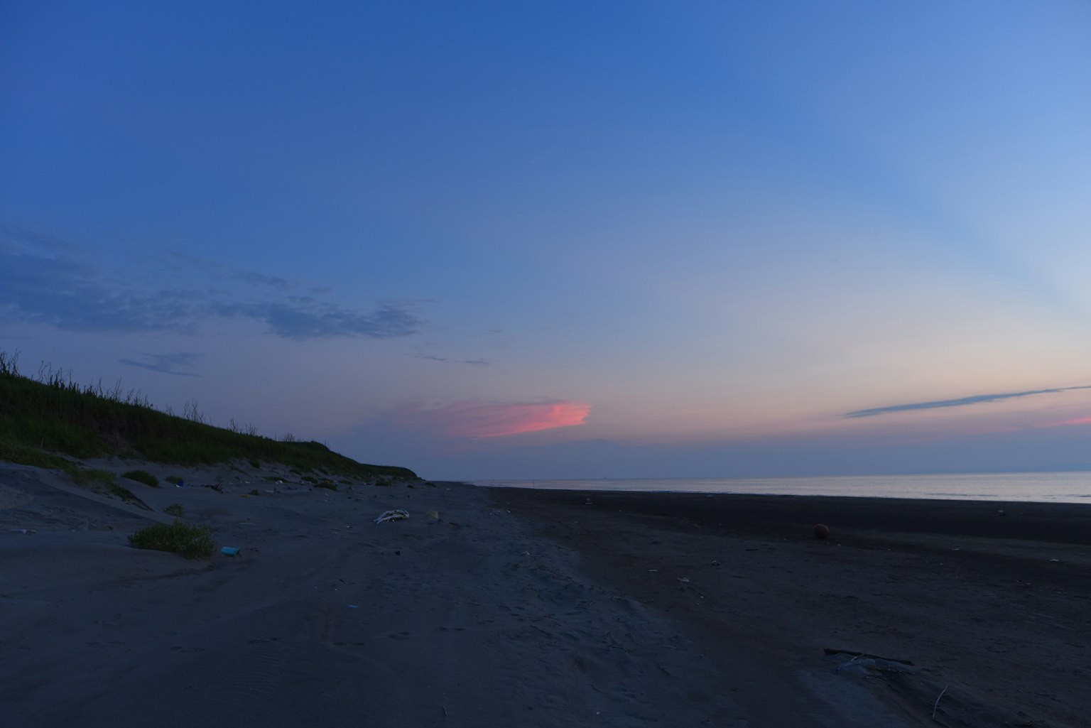 Serene beach sunset with blue sky and soft pink clouds