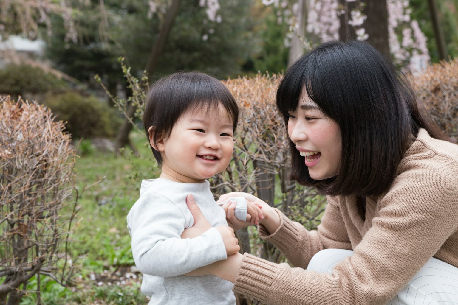 Ein Kind und eine Mutter lächeln und spielen zusammen in einem Park