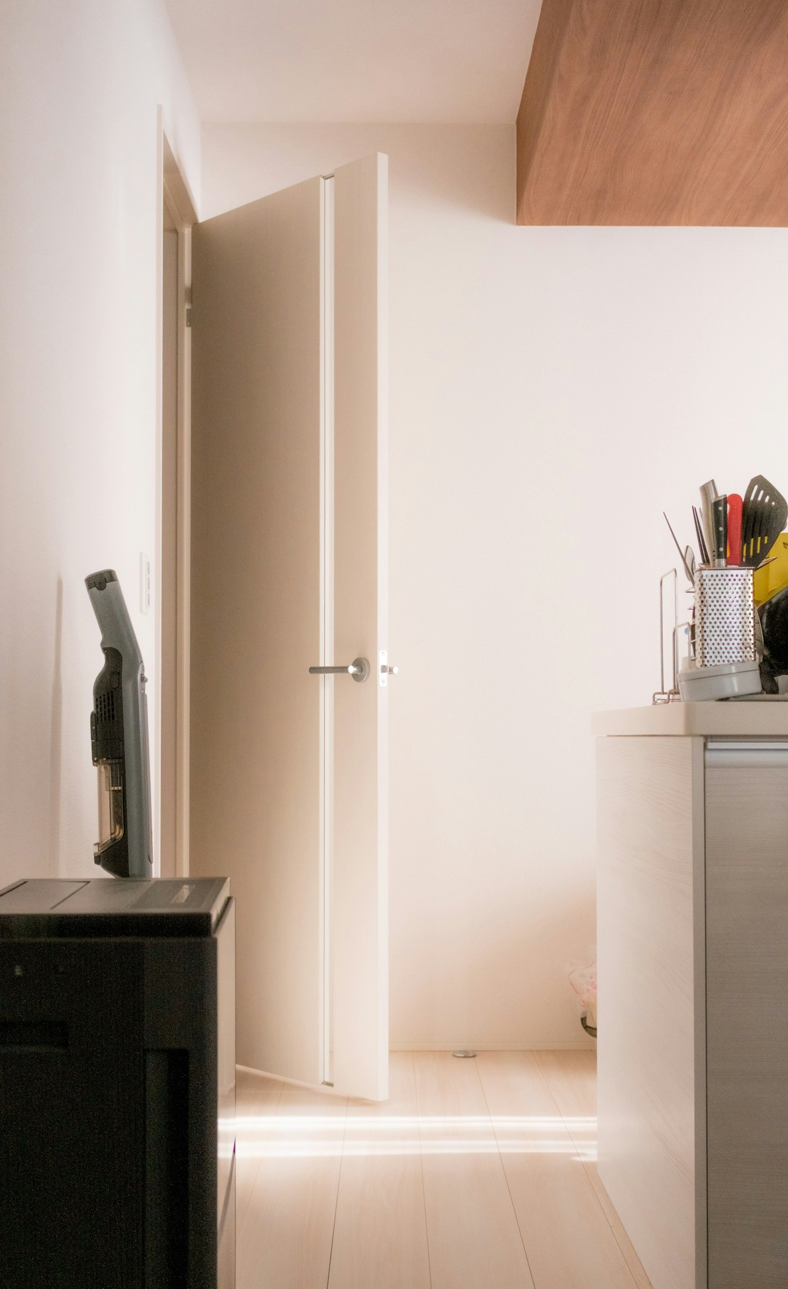 白い壁の部屋のドアが開いているシーン キッチンのカウンターと調理器具が見える