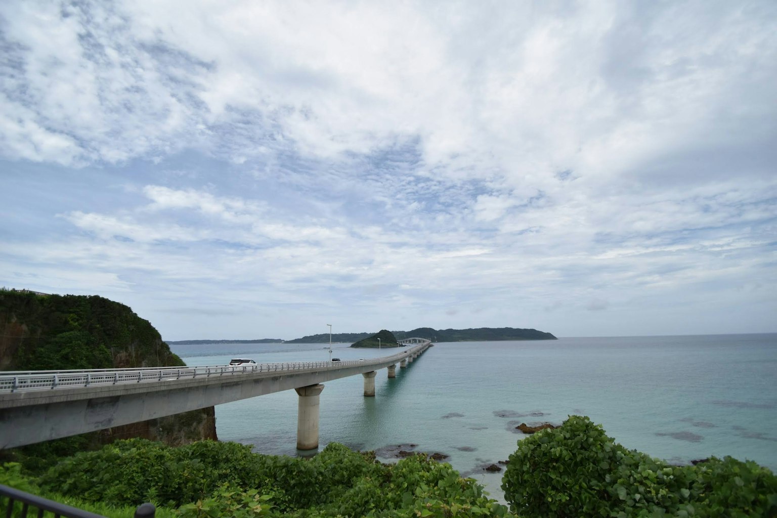 Un puente que se extiende sobre el mar bajo un cielo parcialmente nublado