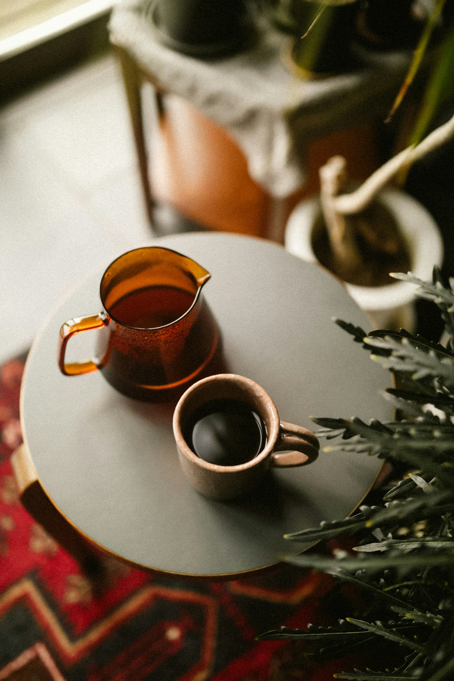 テーブルの上に置かれた茶色のピッチャーとカップ 植物とラグが背景にある