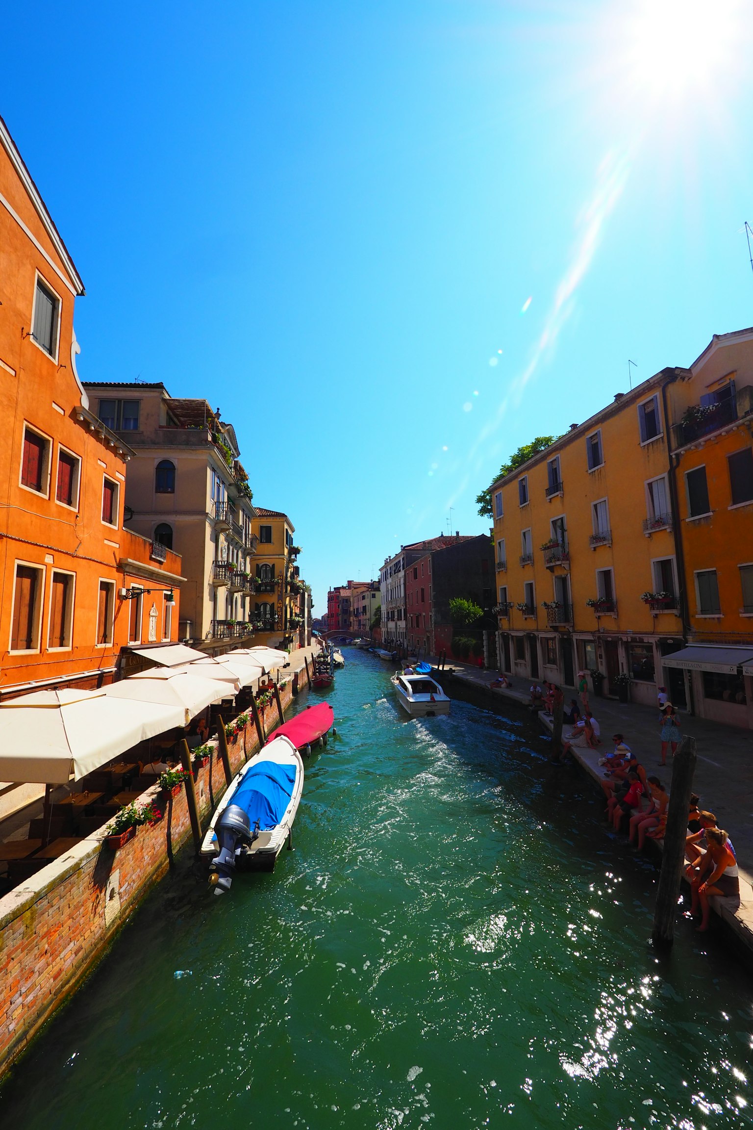 Vibrant orange buildings alongside a sunny canal in Venice