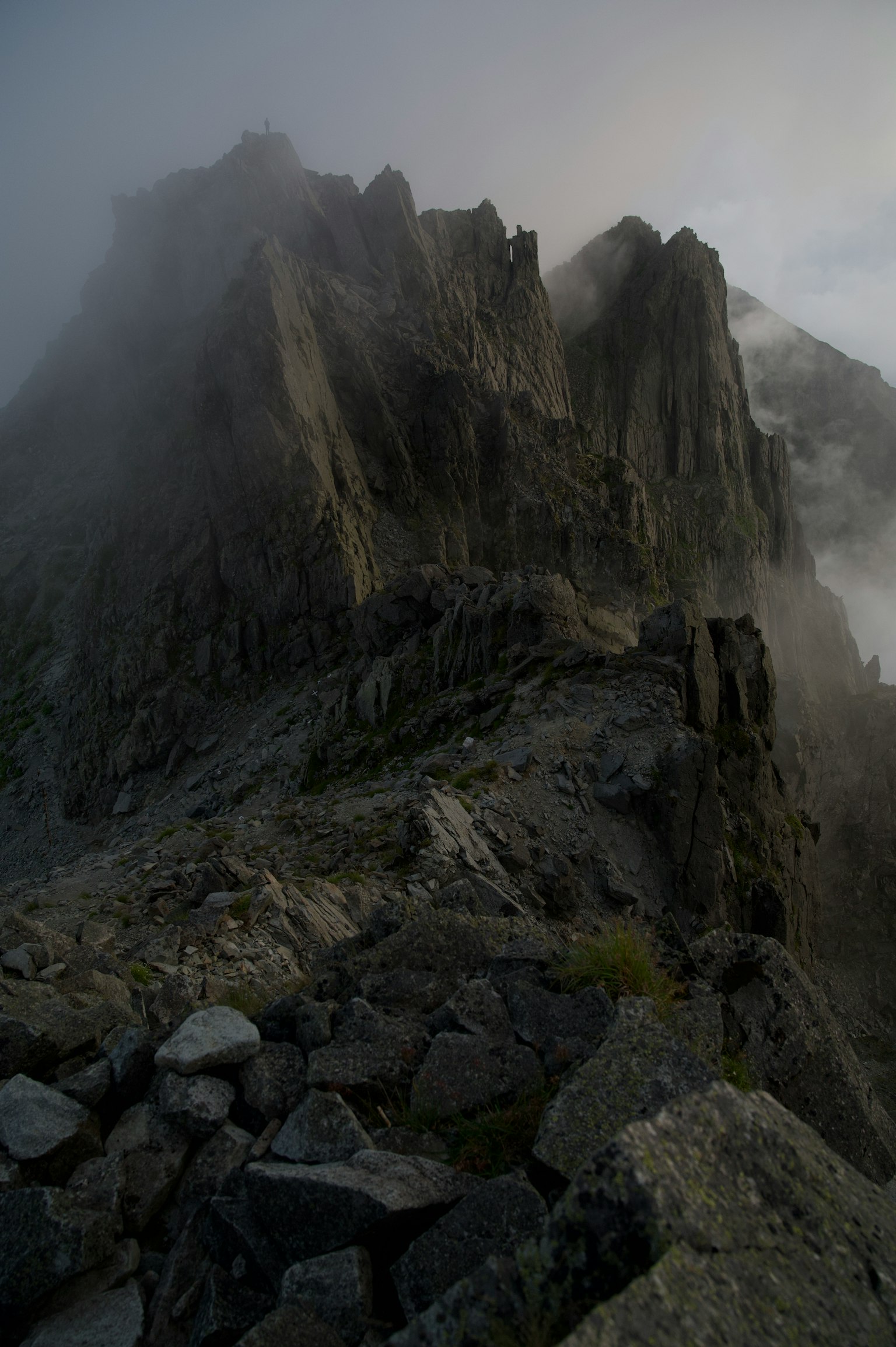 Vista nebbiosa di una cima montuosa impervia e di un terreno roccioso