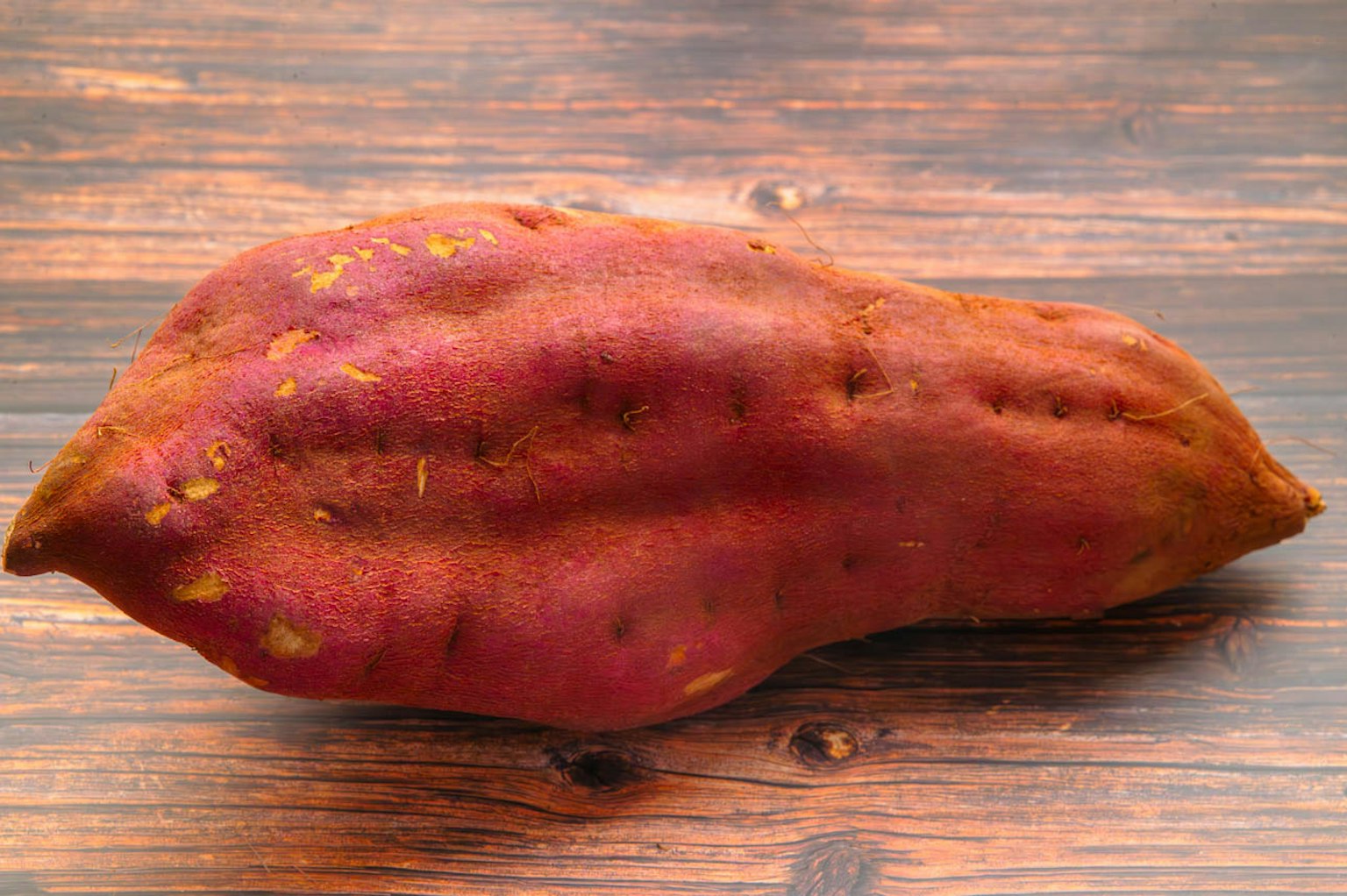 Una patata dolce viola posata su un tavolo di legno